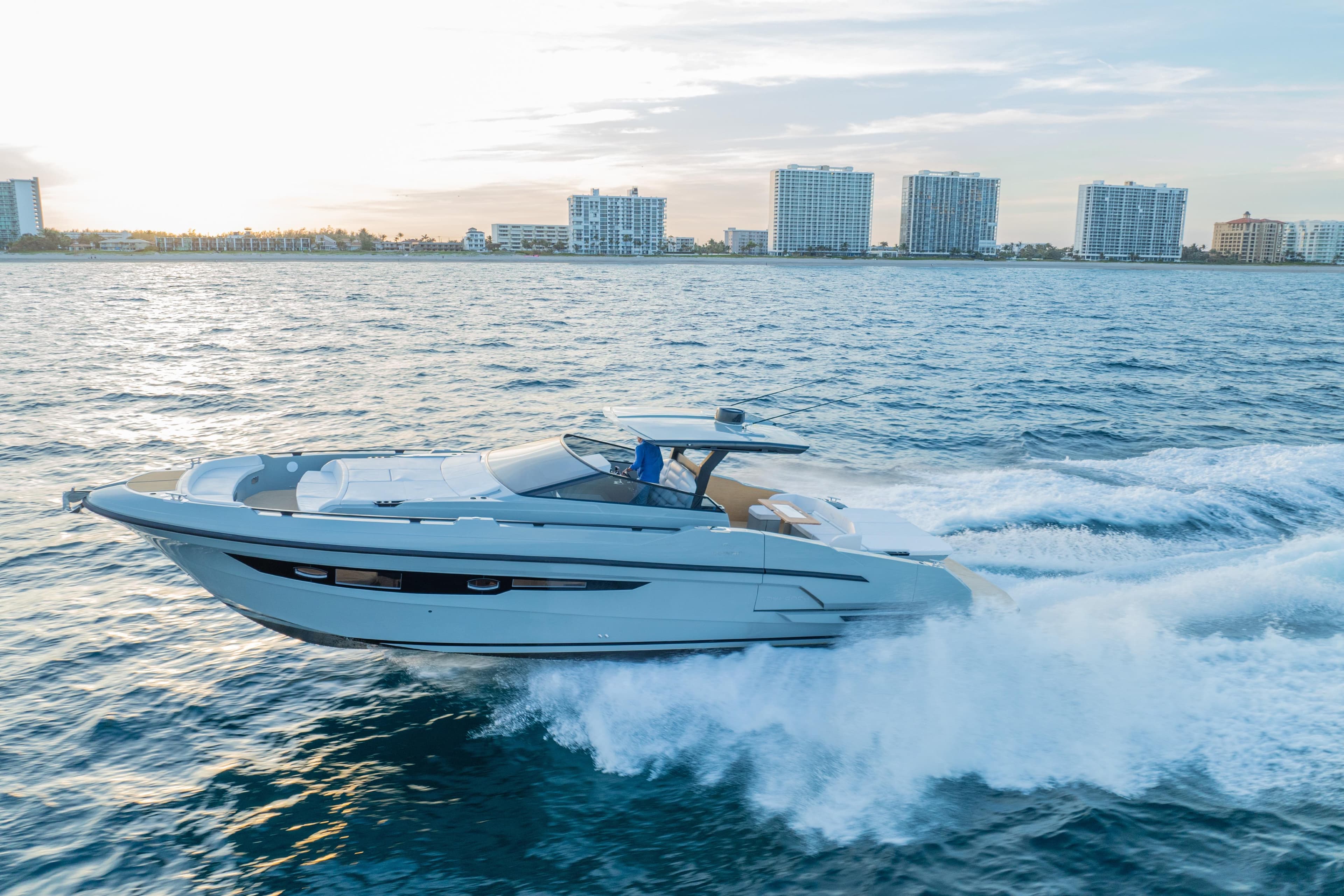 2024 Rio Yachts Daytona 50 cruising on ocean near city skyline at sunset.
