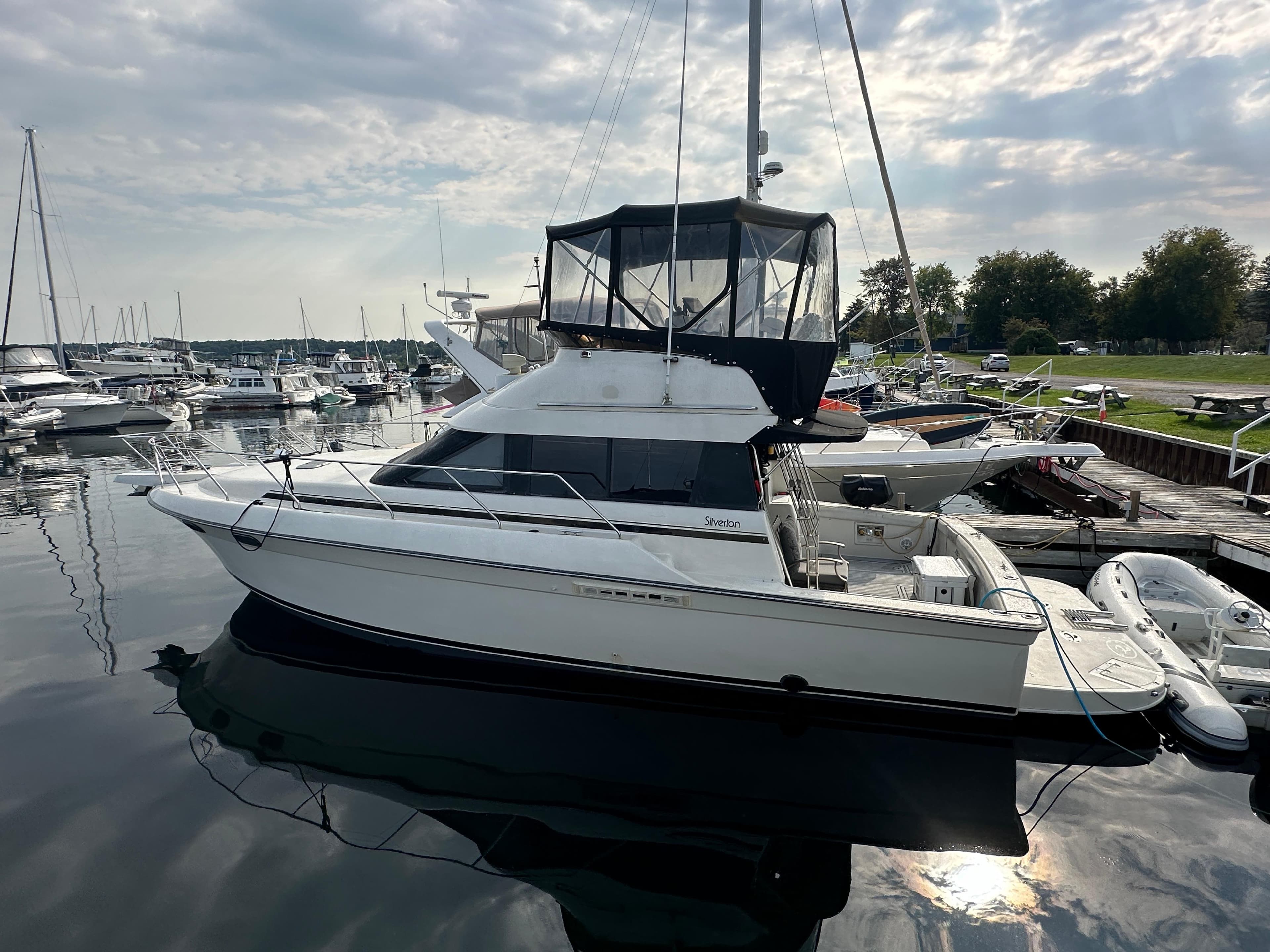 1990 Silverton 37C yacht docked at a marina under a cloudy sky.