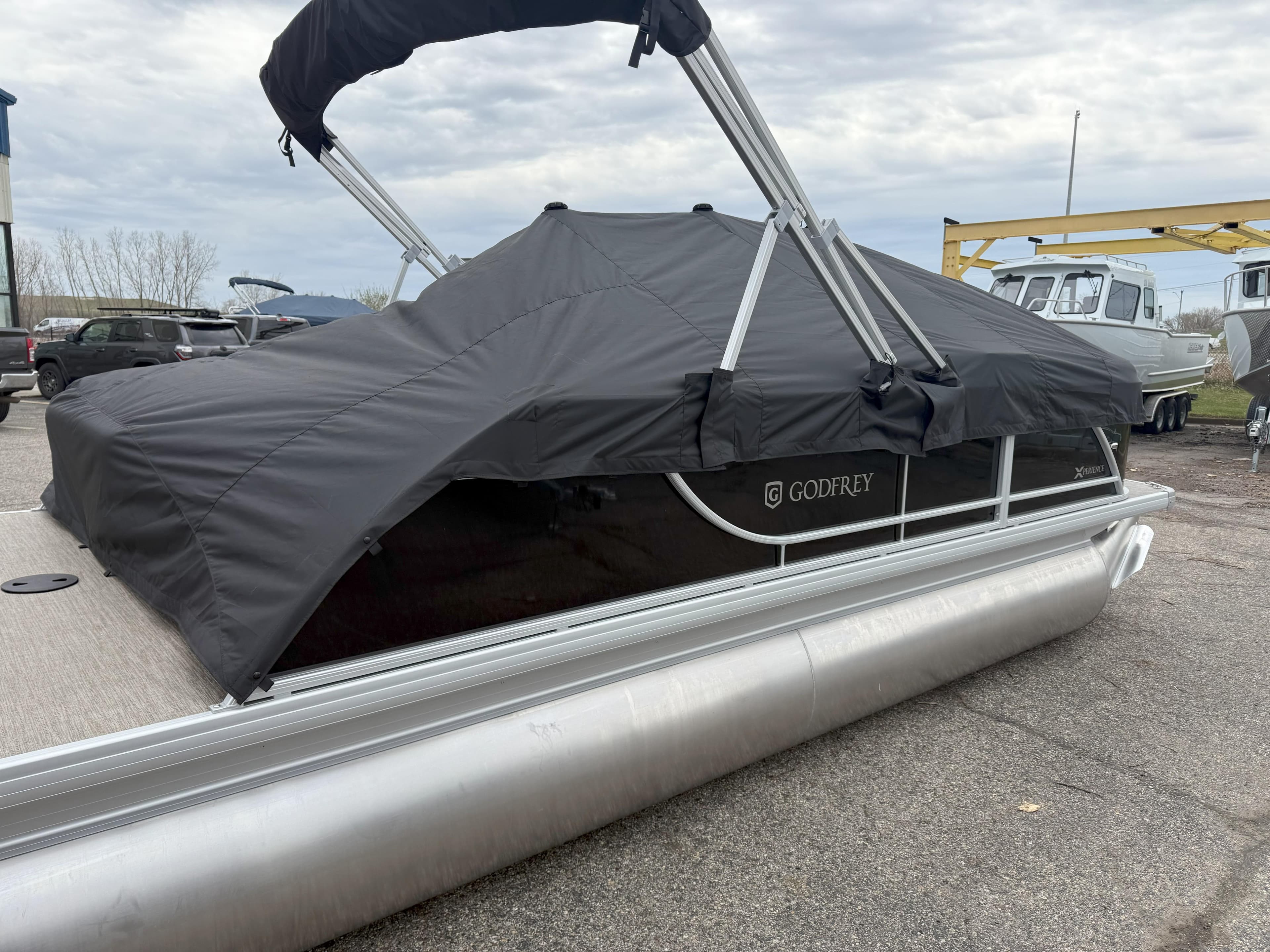 2025 Godfrey EX2086SFLX pontoon boat with black cover, parked on a lot.