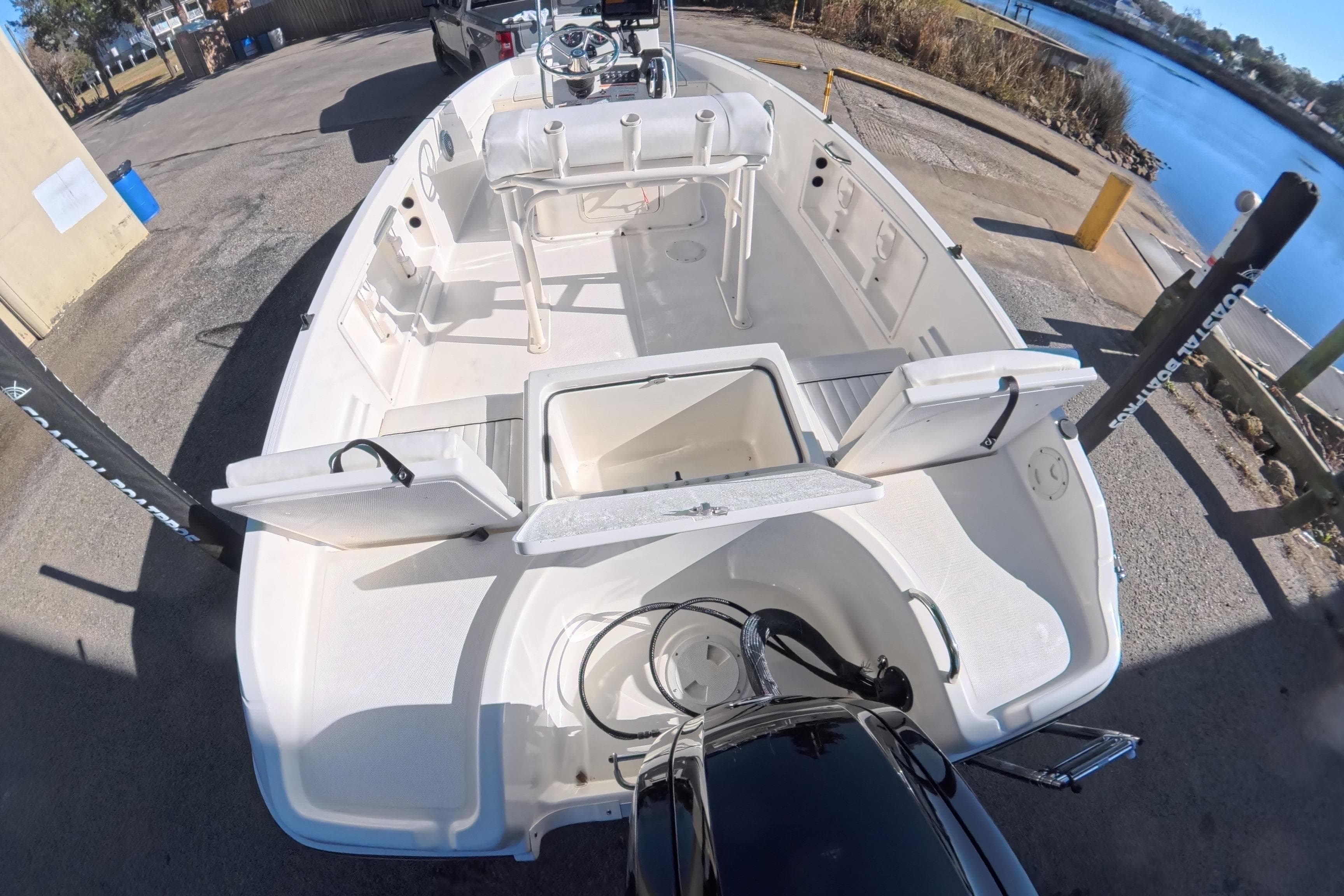 2023 Trophy T-18 boat with open storage compartments, docked by a serene waterfront.