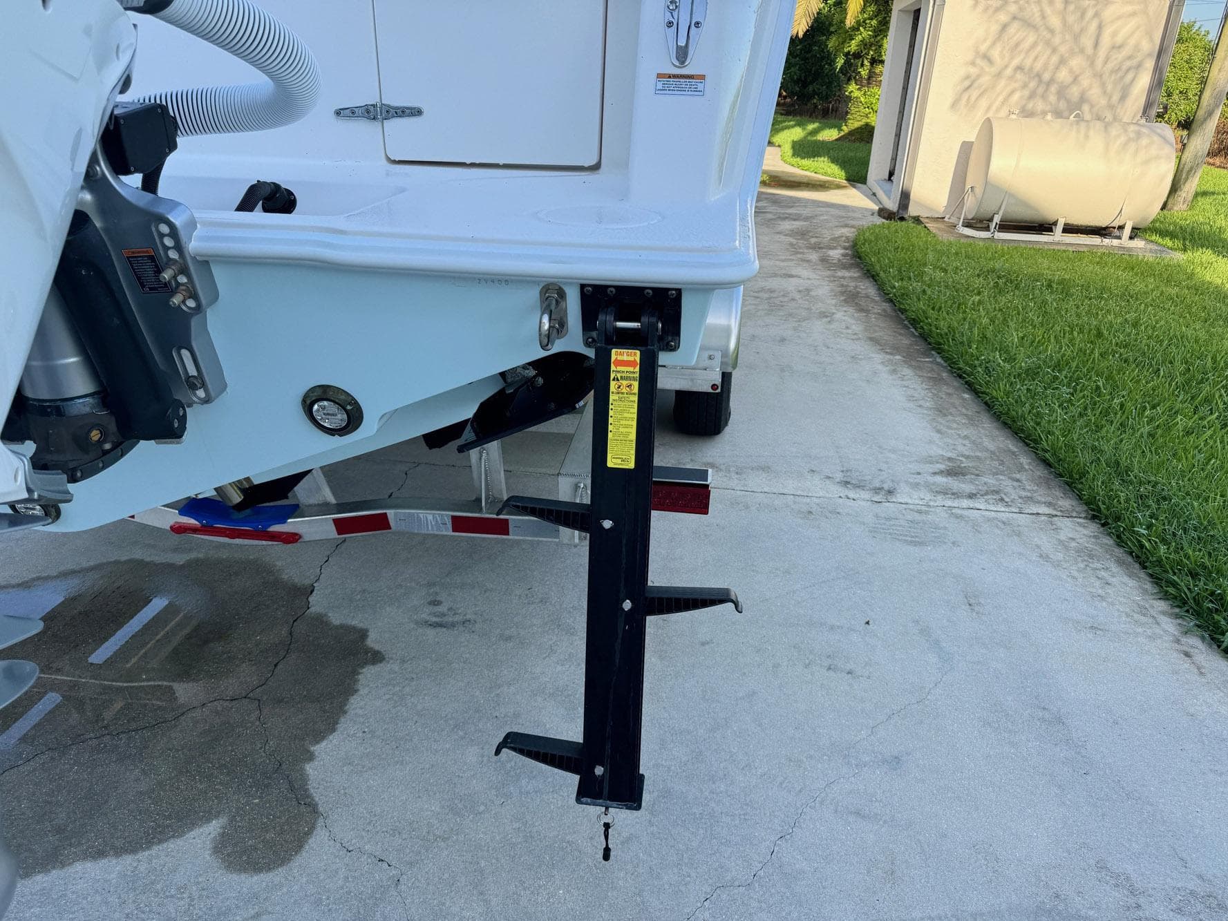 2024 Contender 32 ST boat trailer with support jack on concrete driveway.