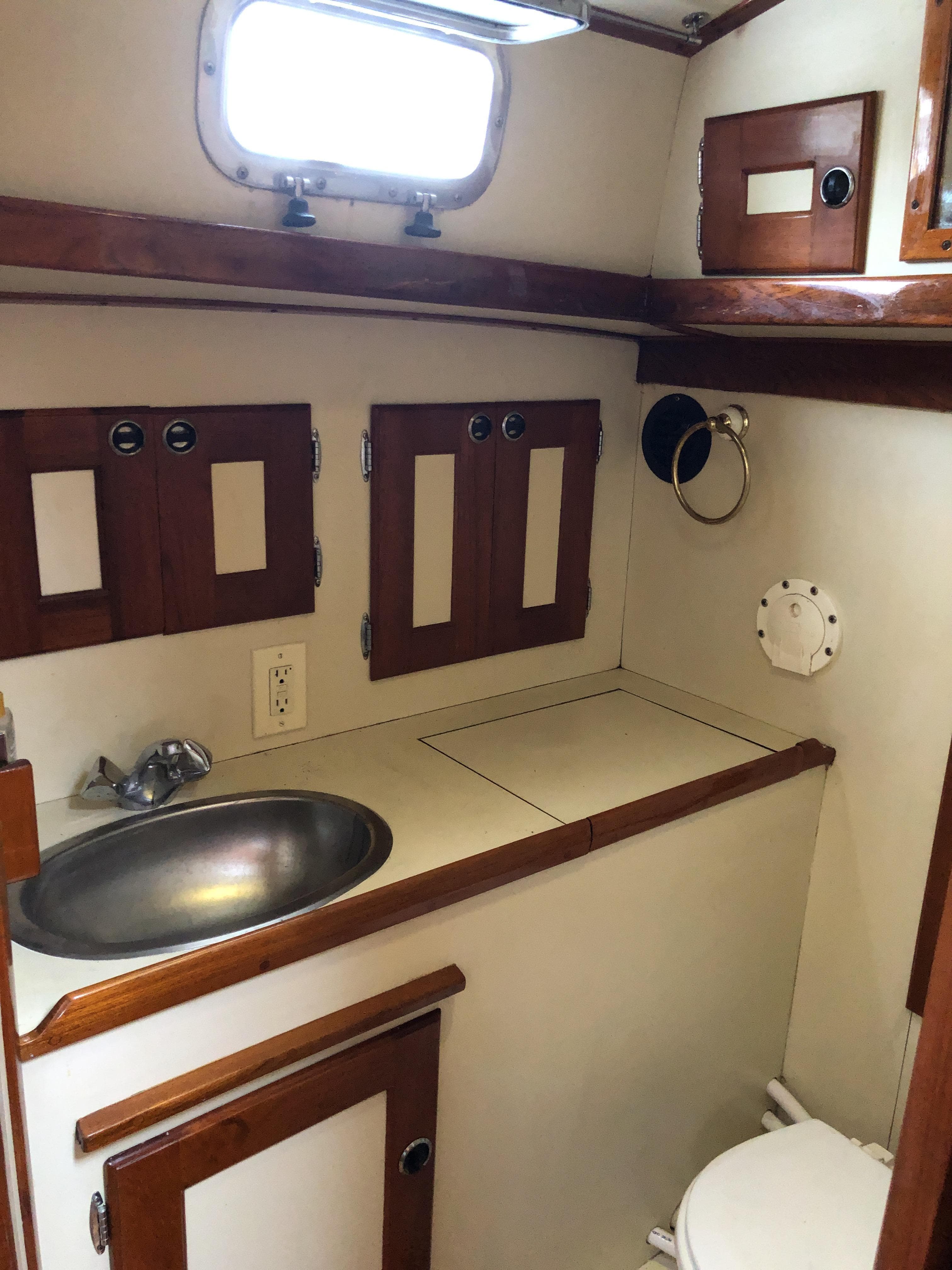 1995 Valiant 50 yacht bathroom with sink, wooden cabinets, and porthole window.