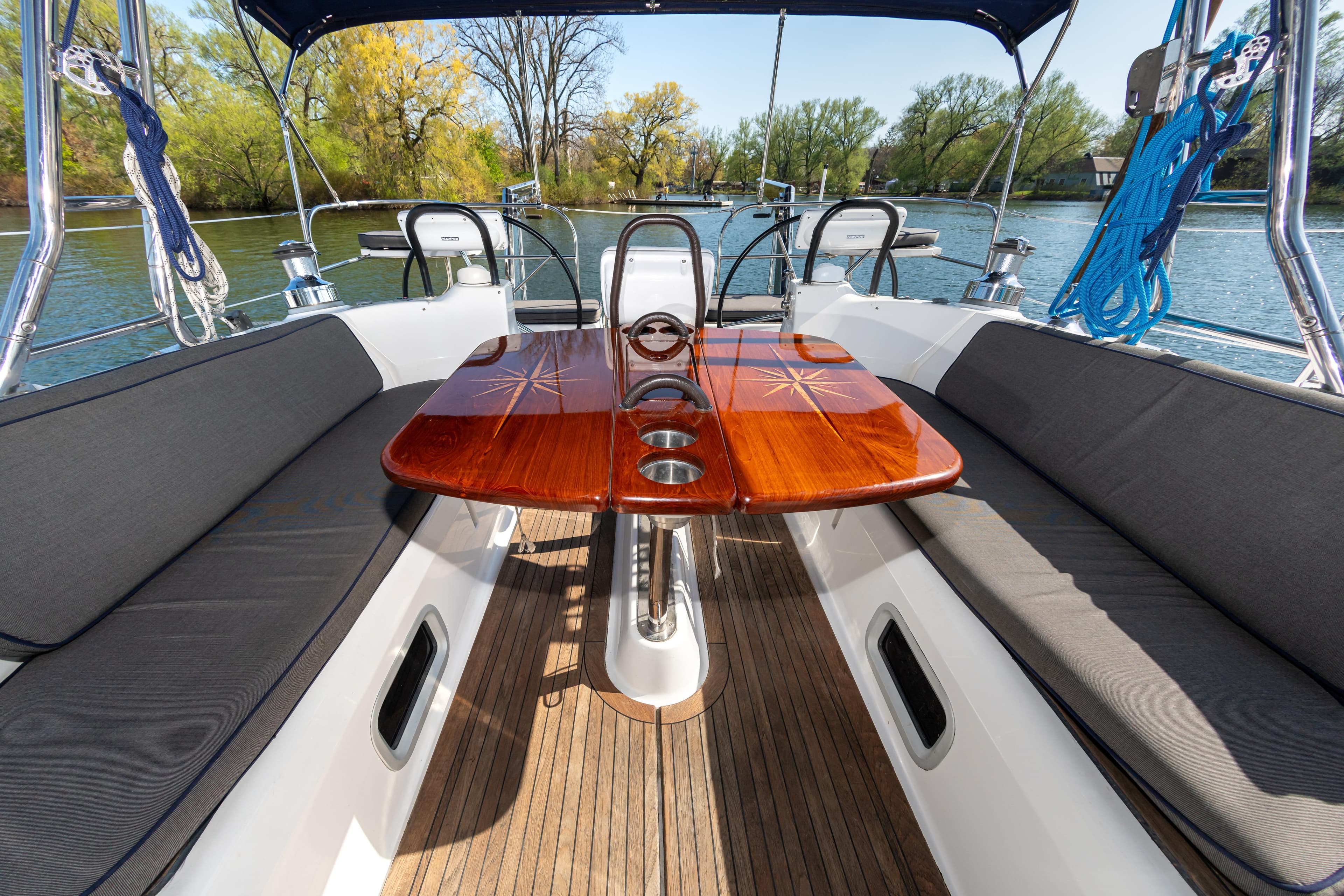 Spacious cockpit of 2007 Hunter 49 sailboat with wooden table and cushioned seating.
