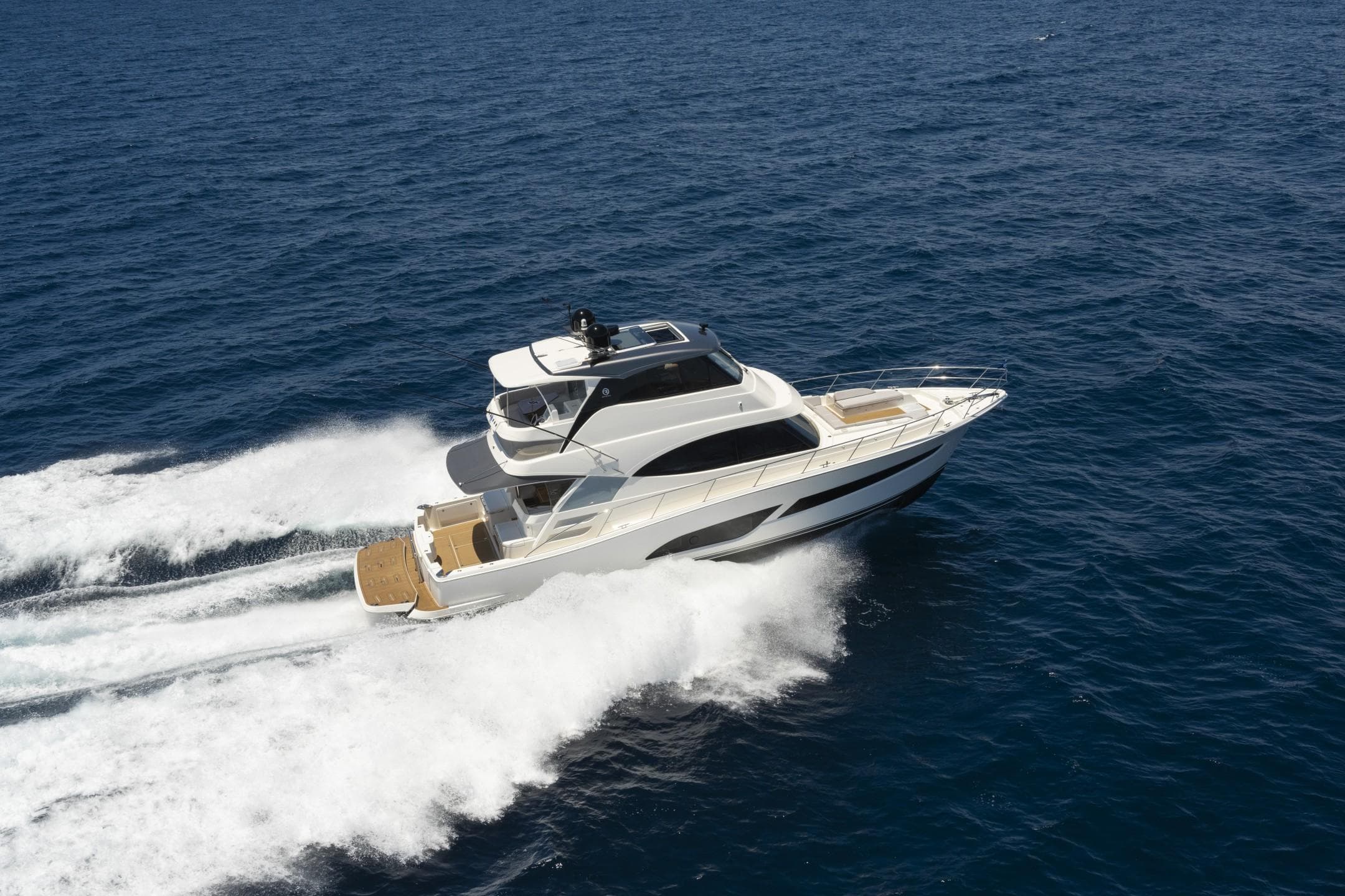 2025 Riviera 58 Sports Motor Yacht cruising on open sea, showcasing sleek design and performance.