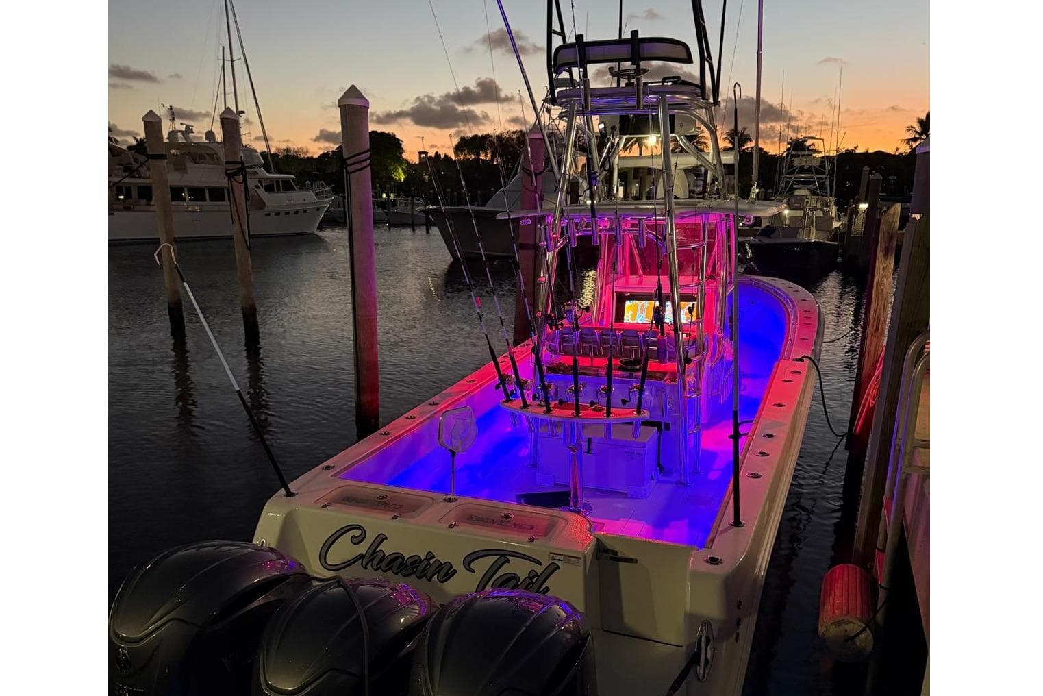 2024 Contender 39 ST boat illuminated at sunset in marina, showcasing vibrant interior lighting.