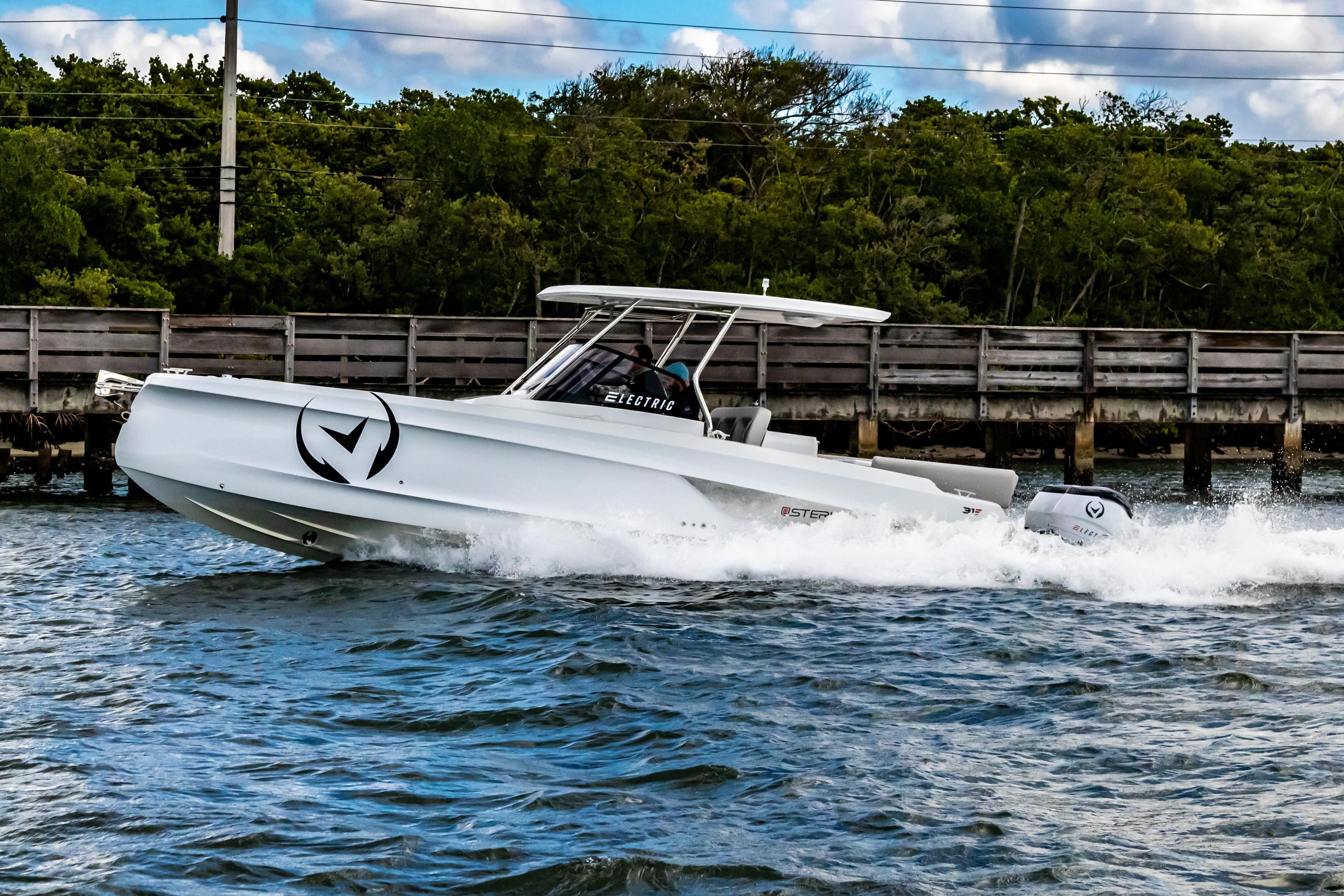 2025 STERK 31 electric boat cruising on water near a wooden bridge.