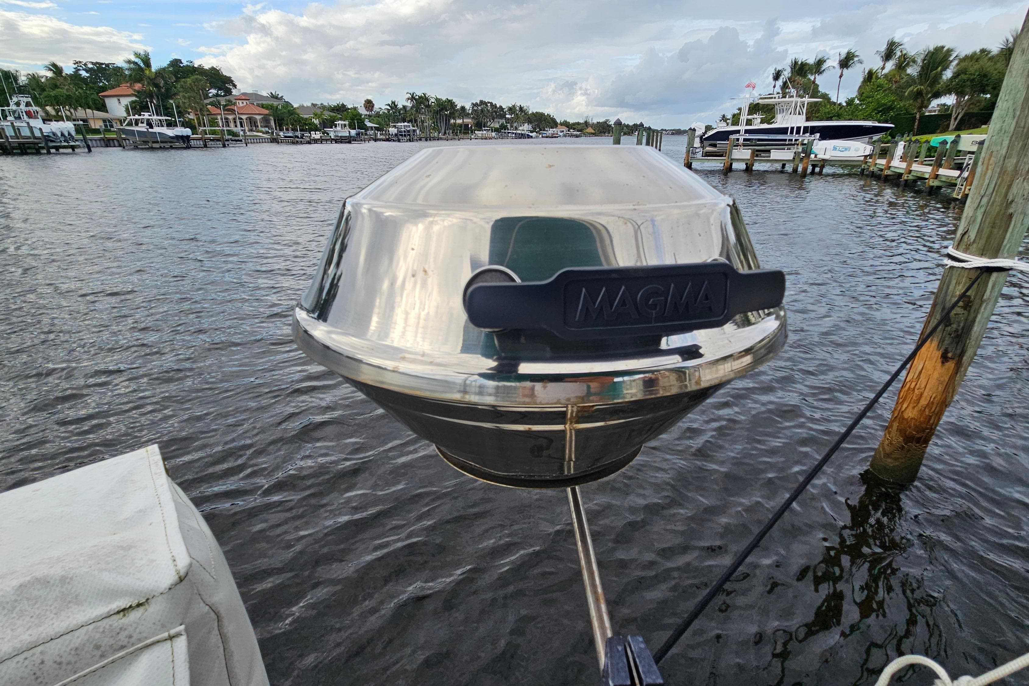 Stainless steel Magma grill on a 1987 Tartan 37 sailboat, docked by a scenic waterfront.