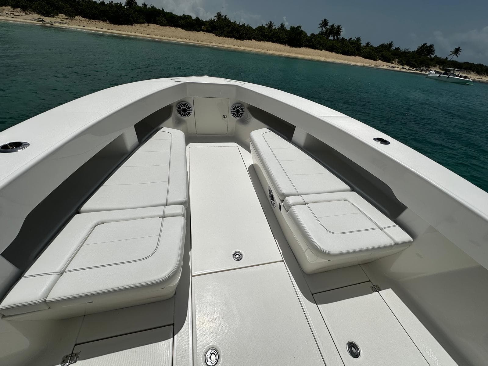 2024 SeaVee 340Z boat interior with white seating, near a tropical beach.