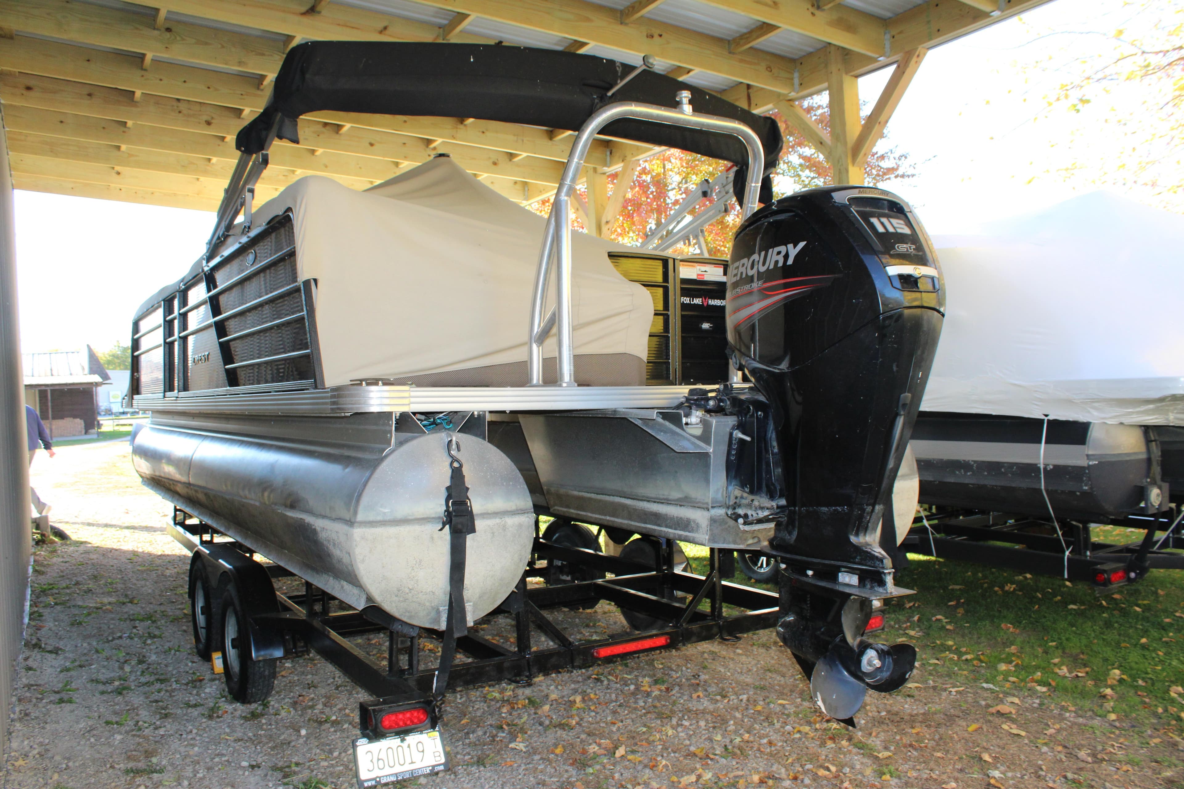 2019 Crest III 240 SLC pontoon boat with Mercury outboard motor under a shelter.