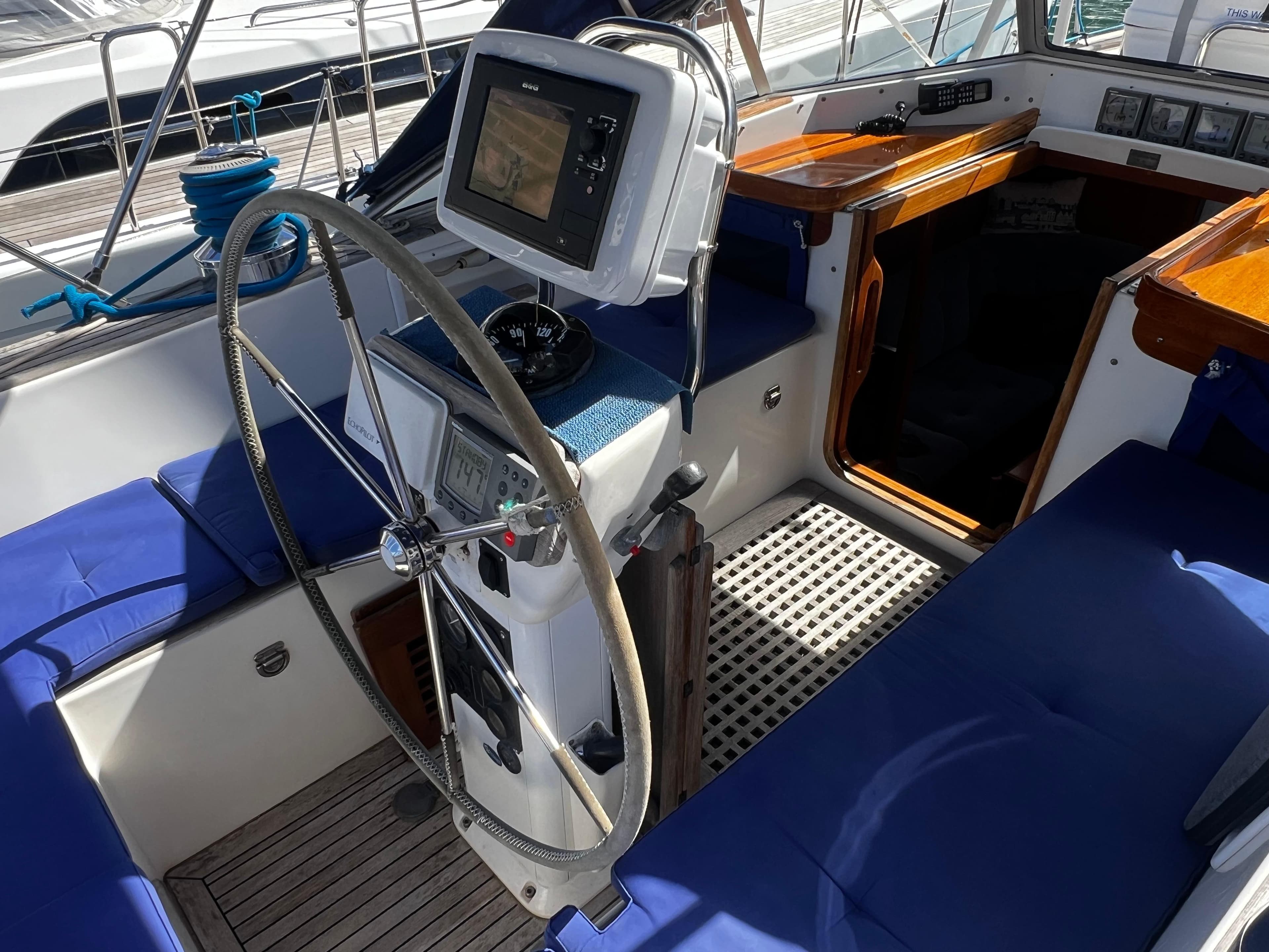 Cockpit of 2001 Hallberg-Rassy 42 sailboat with blue seating and navigation equipment.