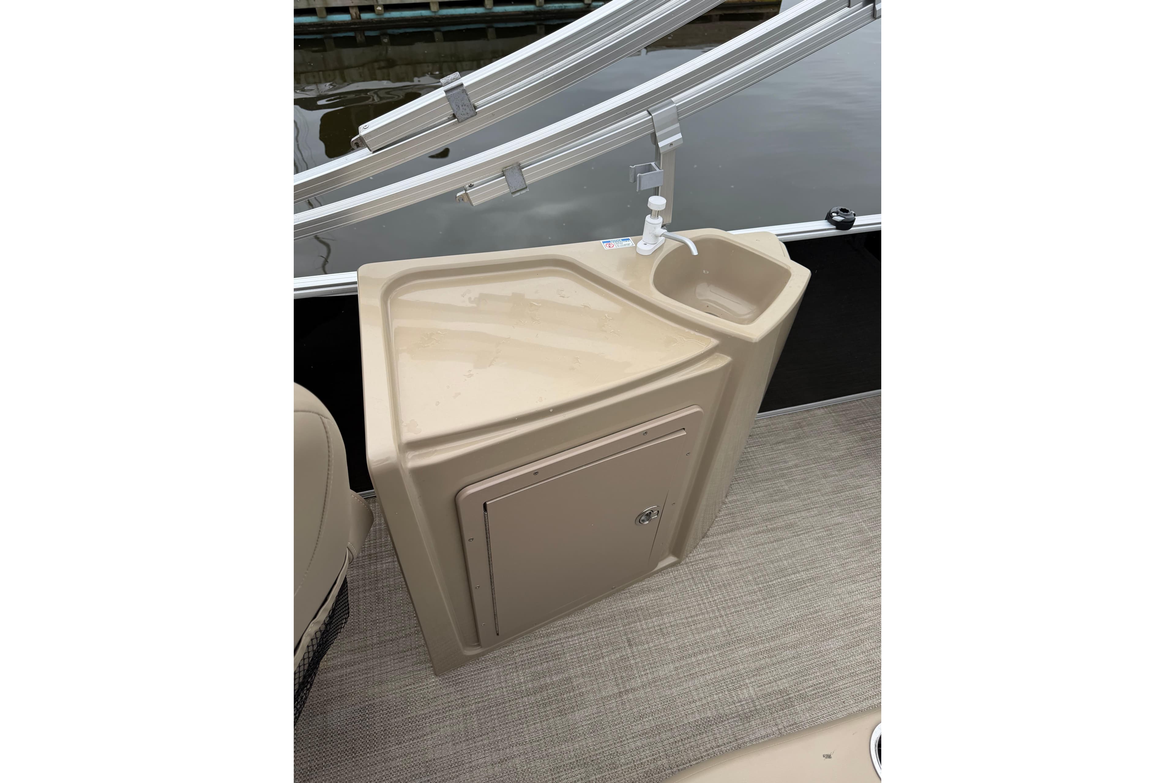 Interior view of 2022 Sylvan Mirage 8522 Resorter boat with a beige sink and storage compartment.