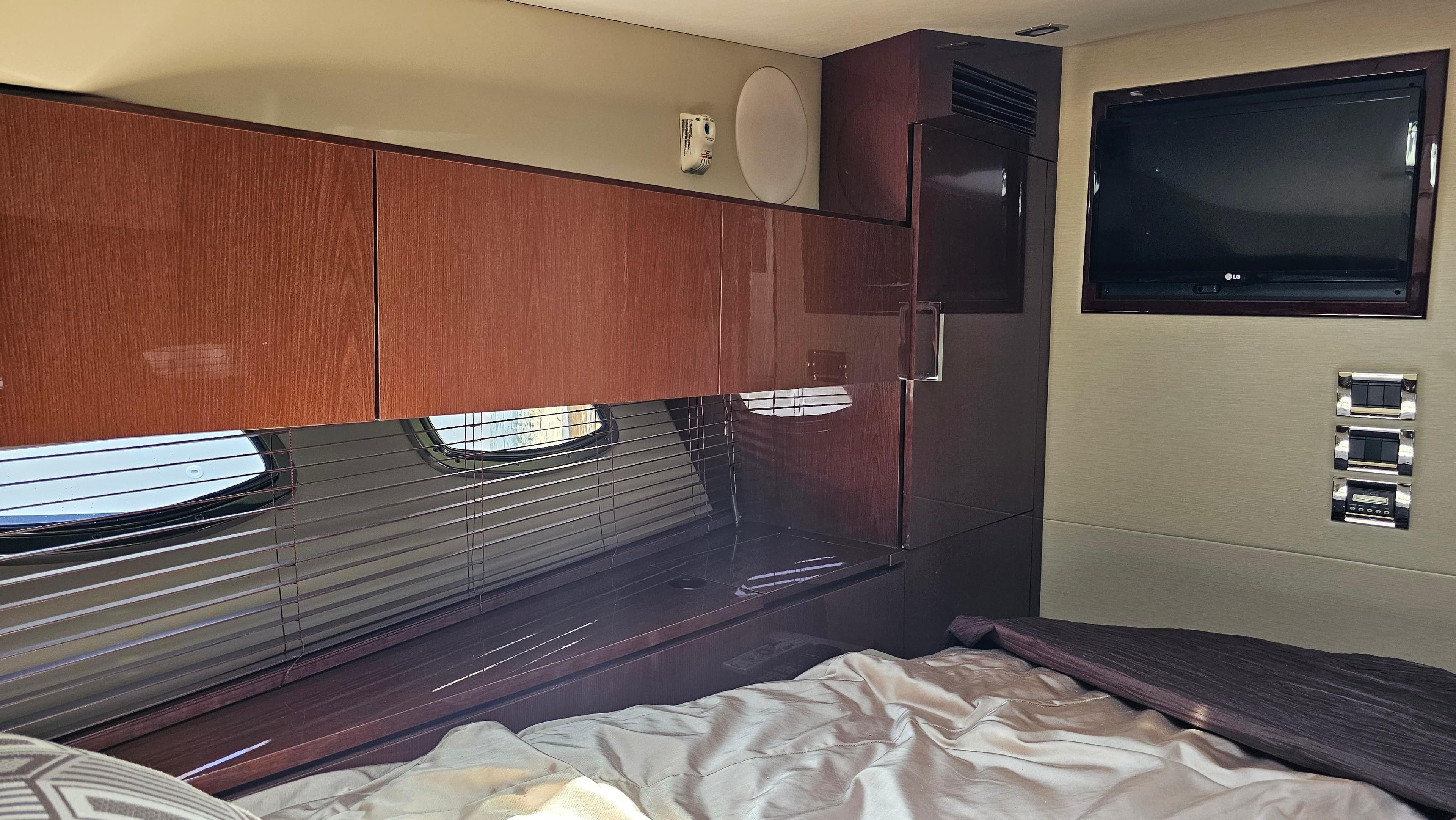 Interior cabin of 2016 Sea Ray 470 Sundancer with wood cabinetry and a mounted TV.