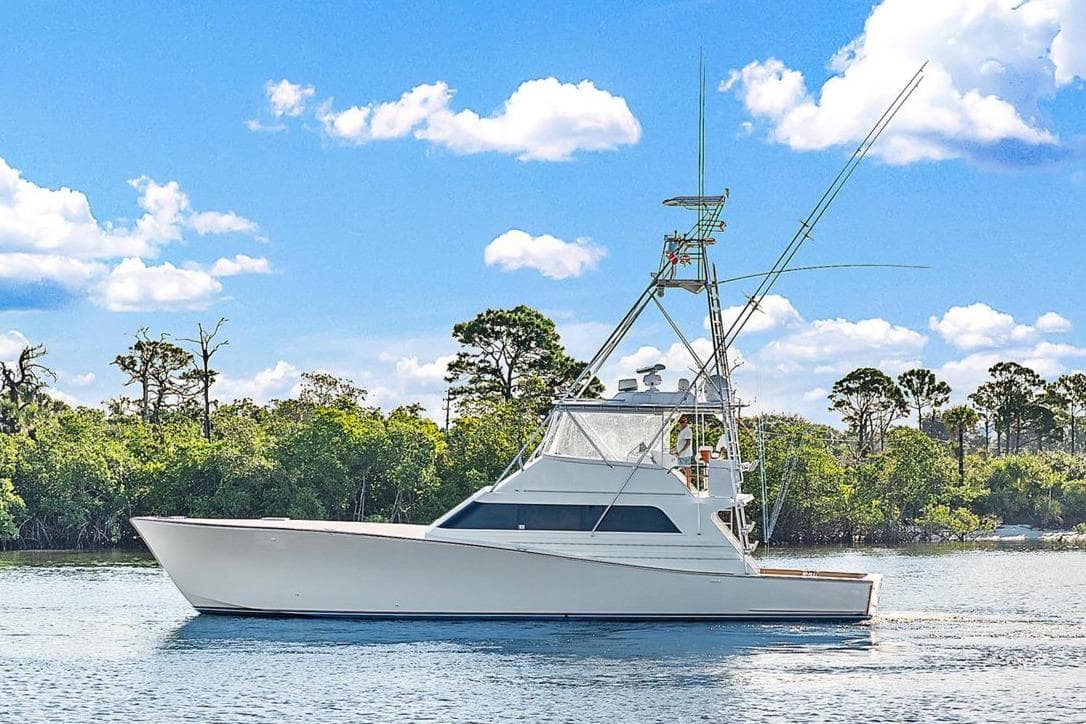 1990 Monterey Custom Sportfish boat on calm water with trees in the background.