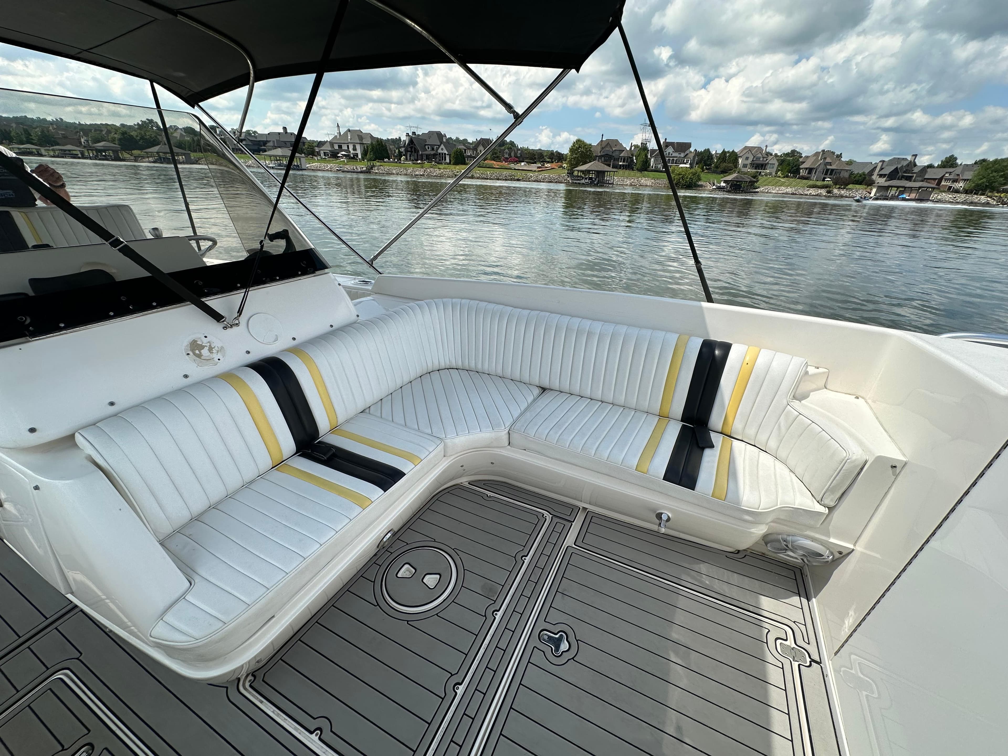 2002 Intrepid 323 Cuddy boat interior with striped seating, lake view, and overcast sky.