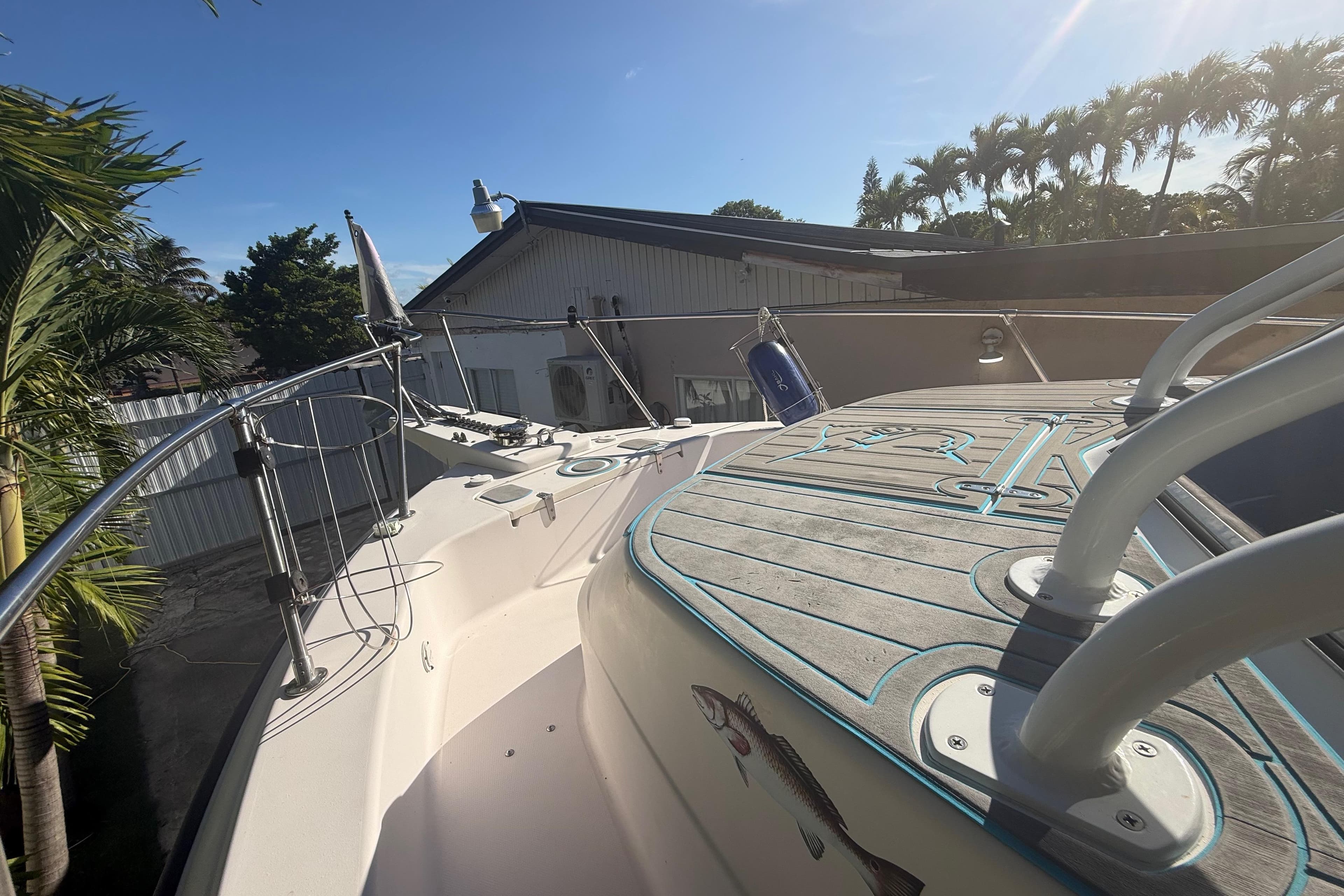 1996 Grady-White Sailfish 272 boat deck with railing, docked near palm trees.