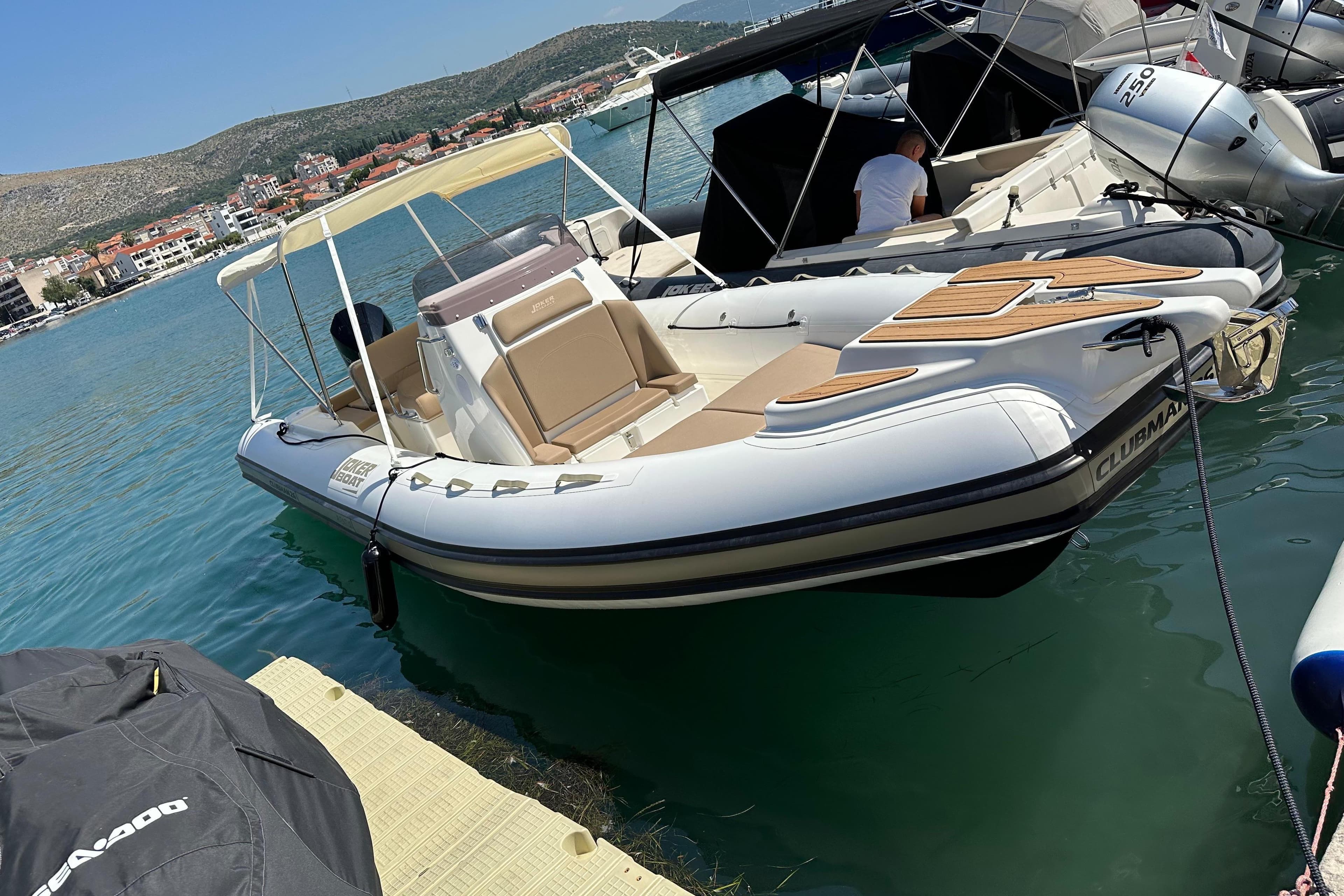 2023 Joker Boat Clubman 26 docked in a scenic marina setting.