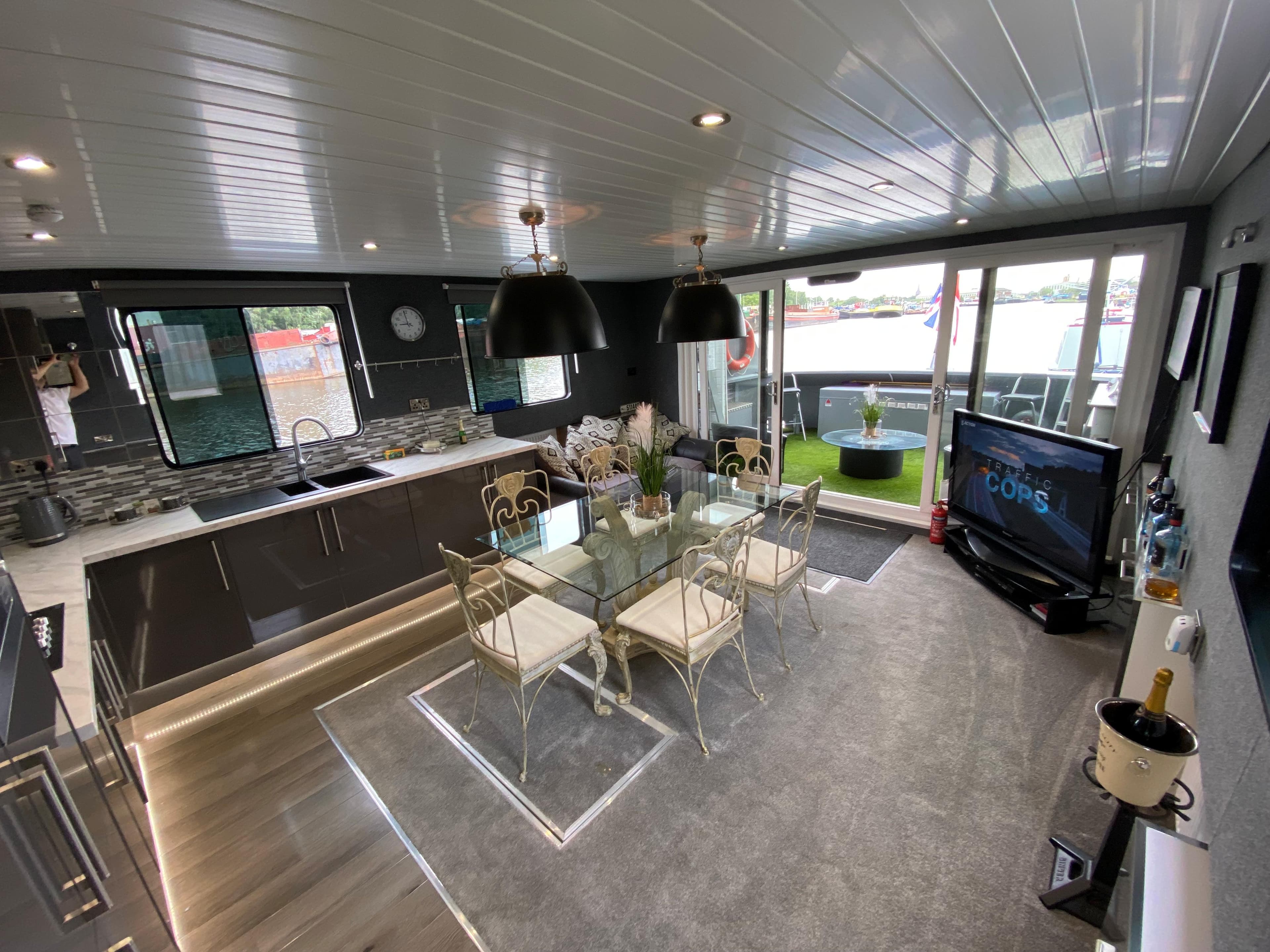 Modern interior of 2002 Widebeam Barge with kitchen, dining area, and large windows.