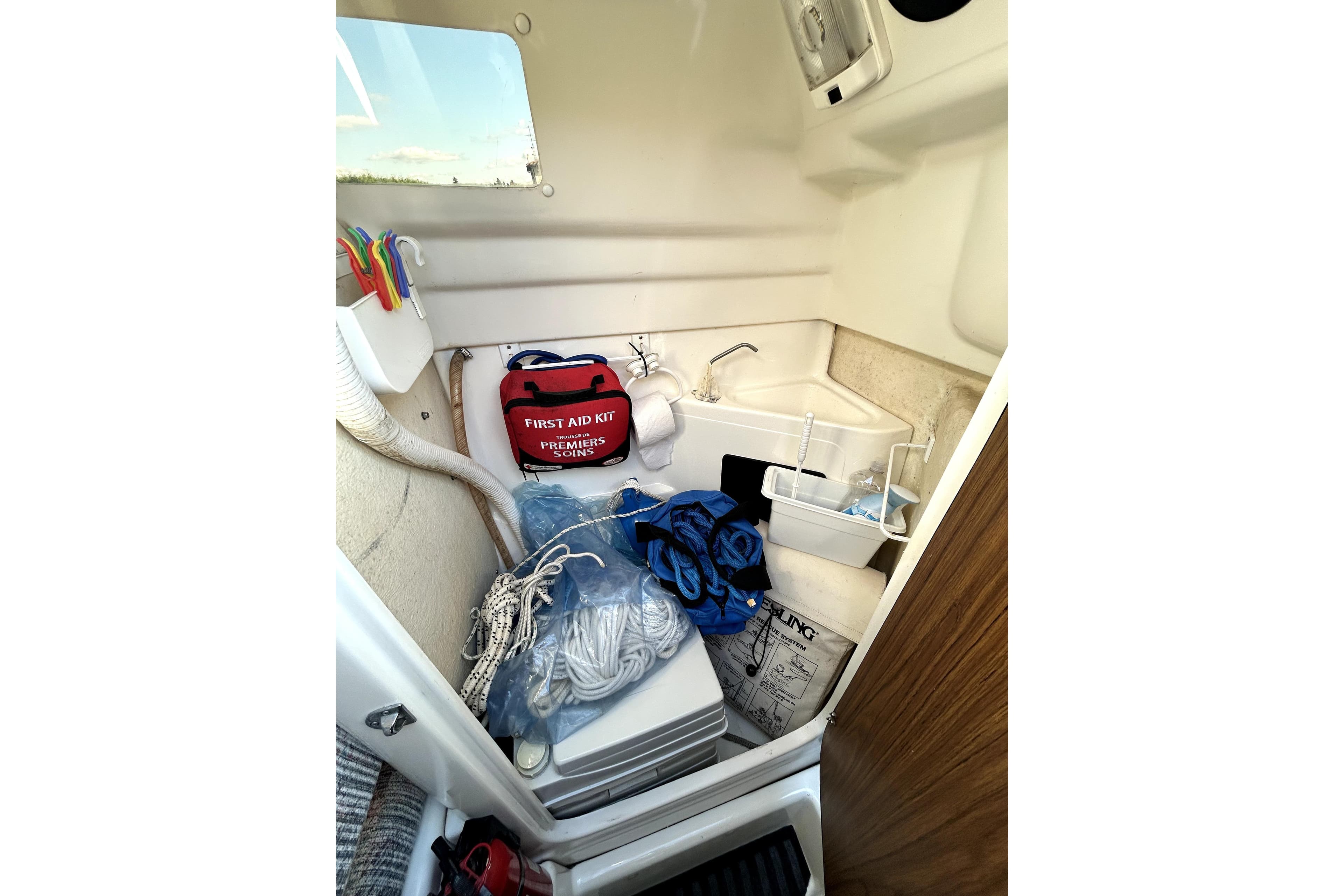 Interior of 1998 MacGregor 26X Powersailer with first aid kit and nautical equipment.