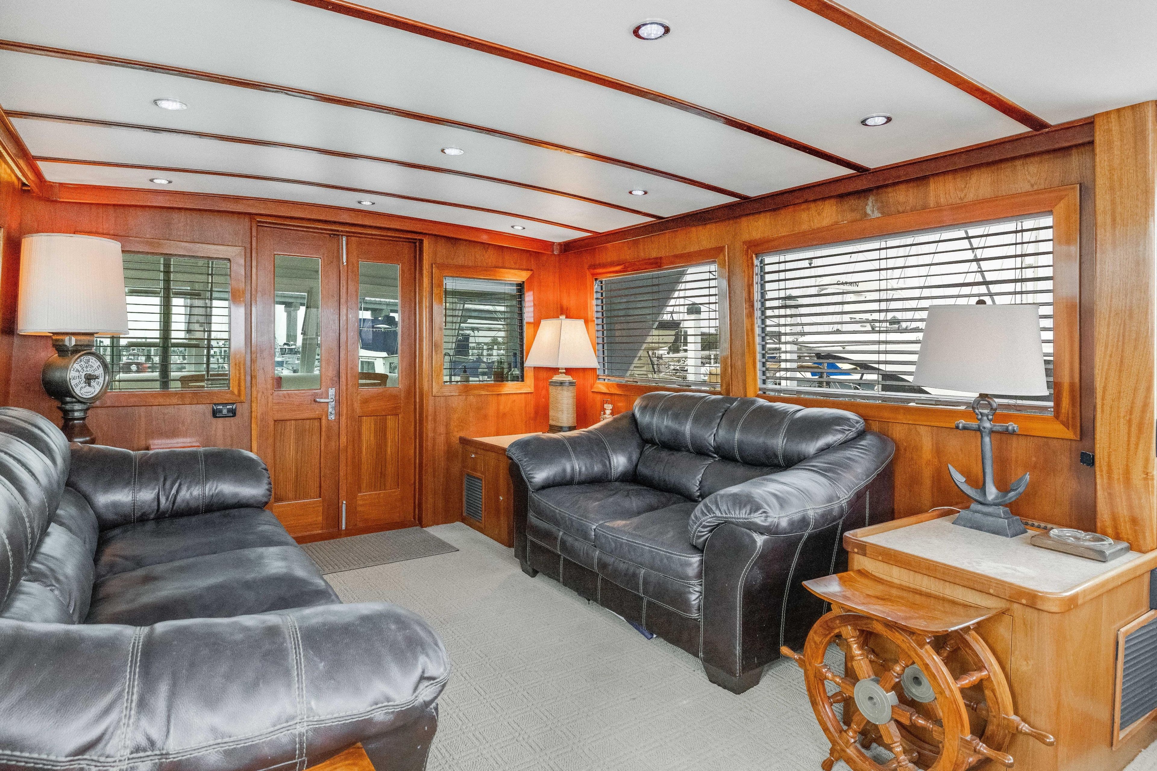Luxurious interior of a 1980 Hatteras 53 Motor Yacht with leather sofas and wooden accents.