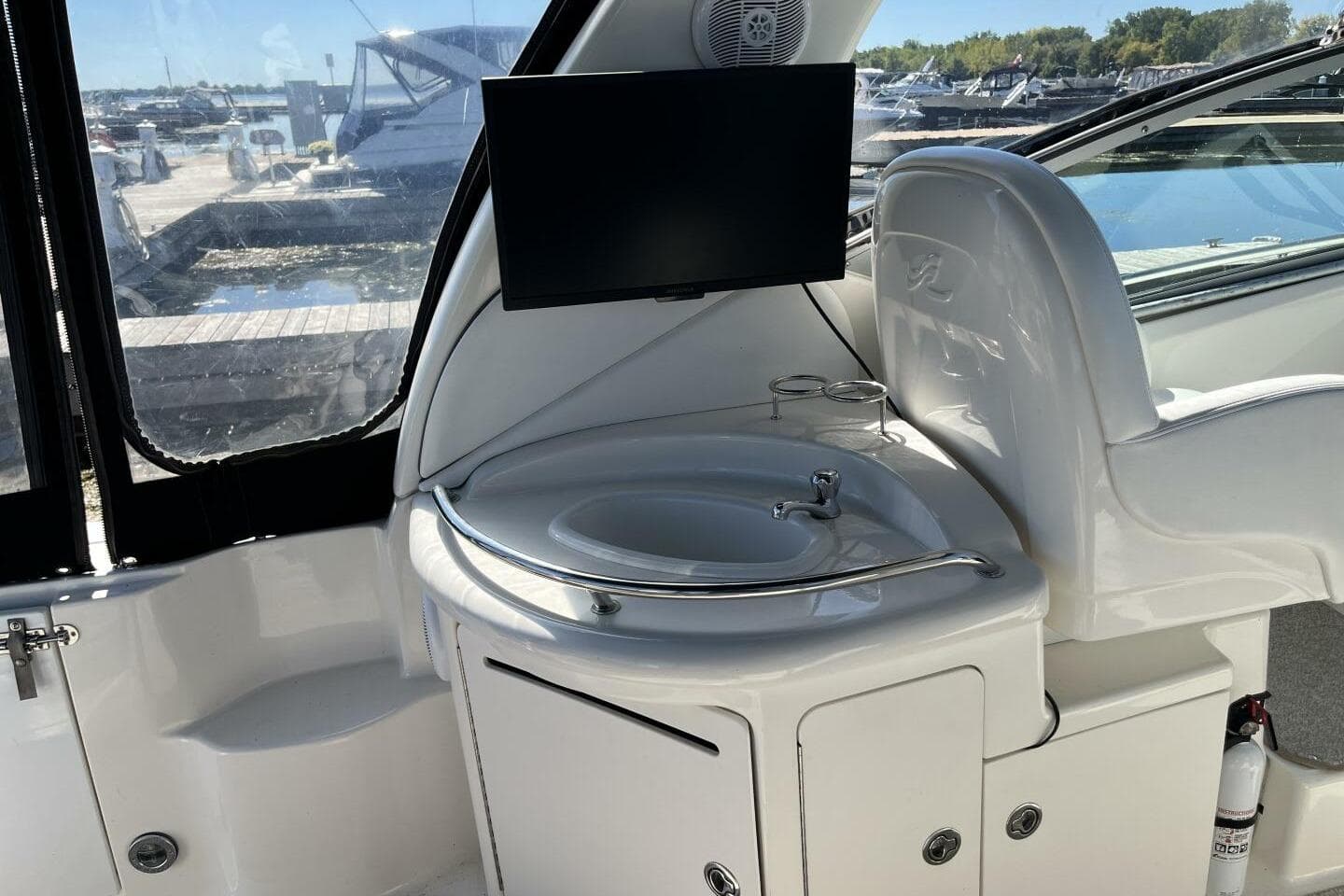 2007 Sea Ray 340 Sundancer interior with sink, TV, and marina view.
