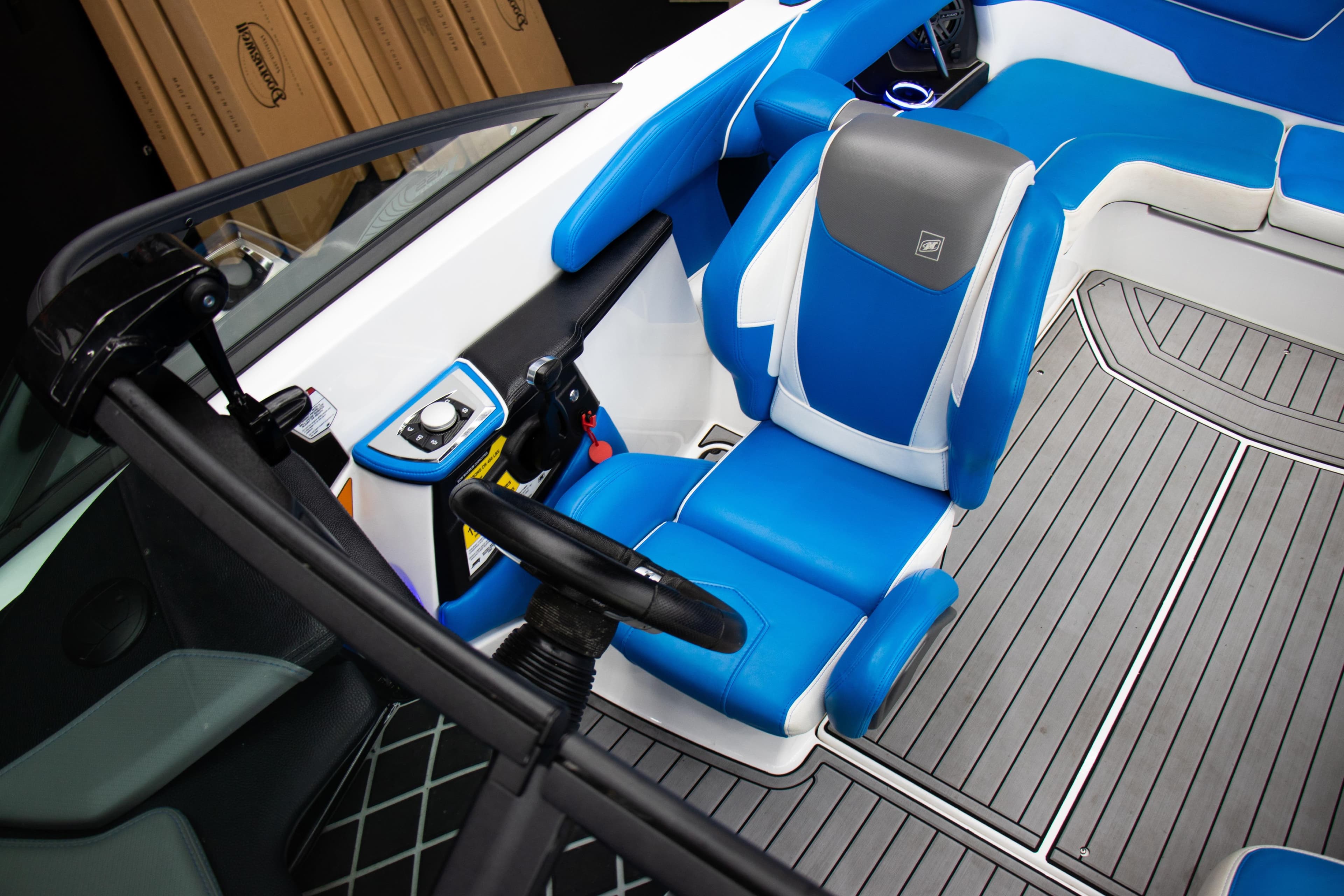 2018 Nautique Super Air Nautique GS22 interior with blue and gray seating, steering wheel, and controls.