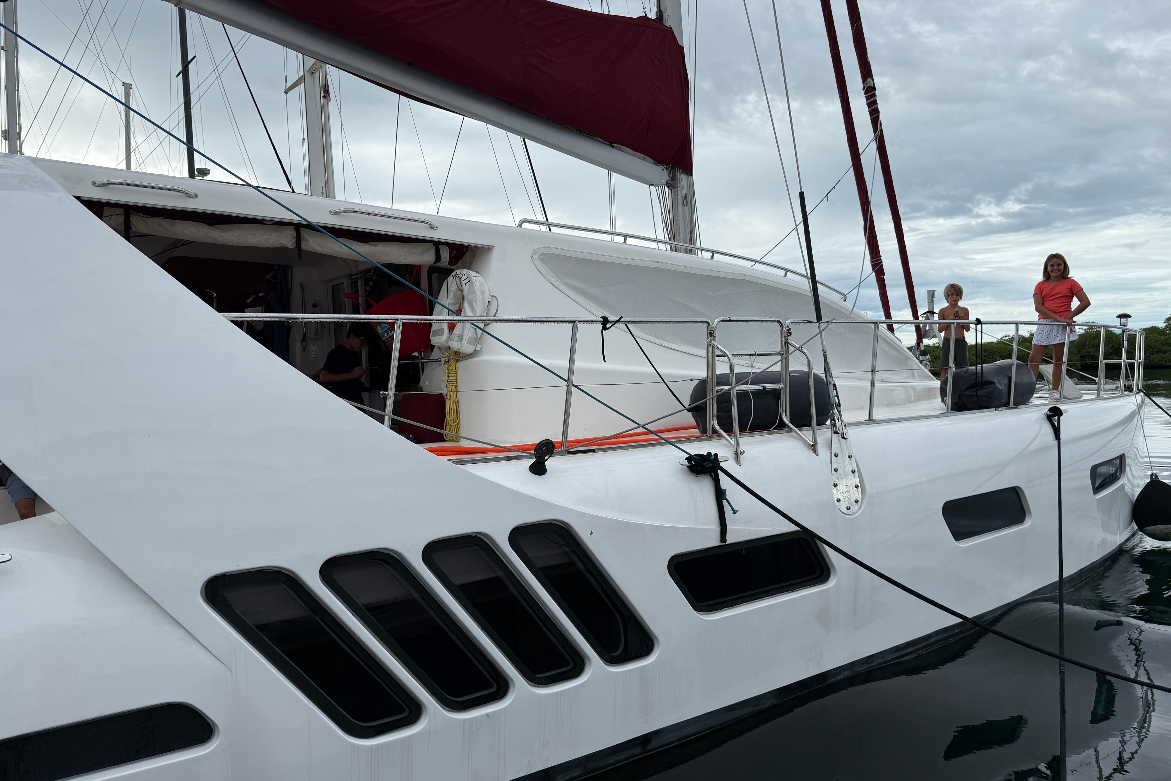 Sailing catamaran Dean 5000, 2012 model, docked with people on deck.
