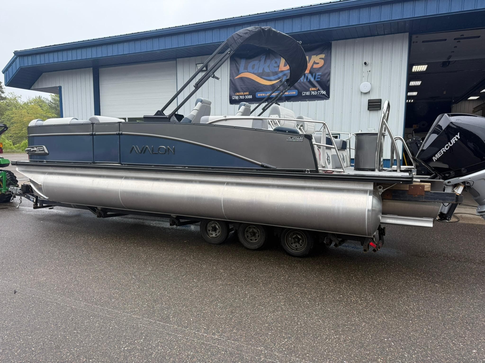 2025 Avalon Catalina Quad Lounger Shift pontoon boat on trailer outside a blue building.