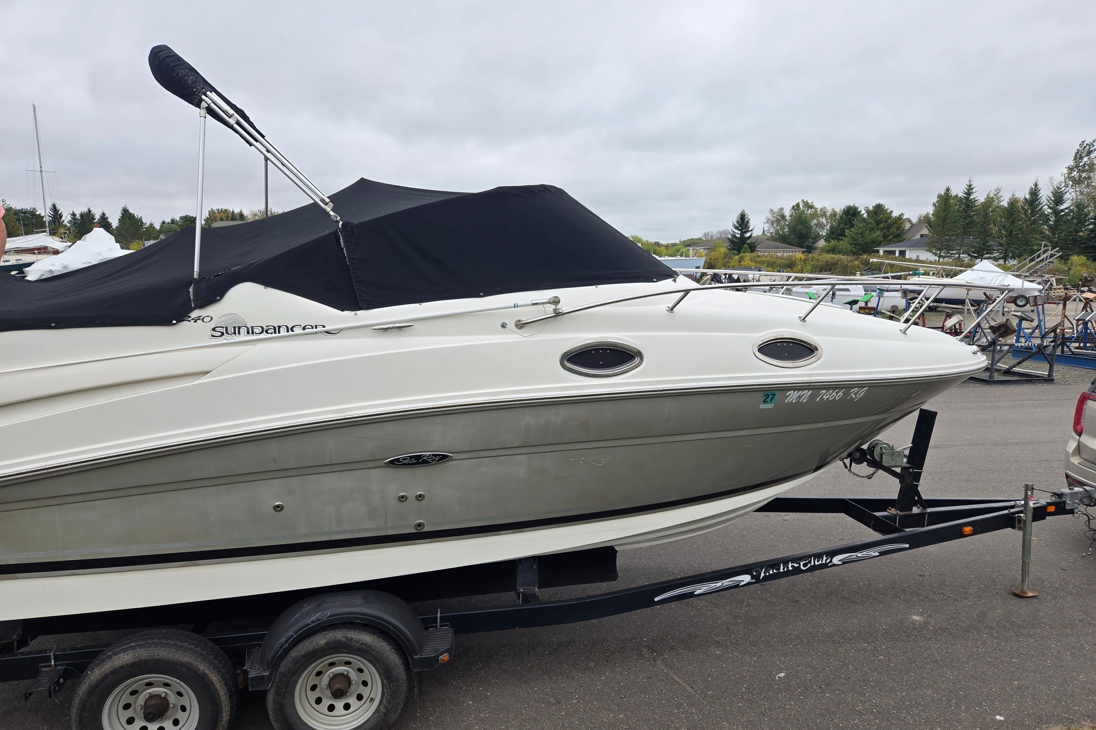 2007 Sea Ray 240 Sundancer boat on trailer, covered and parked outdoors.