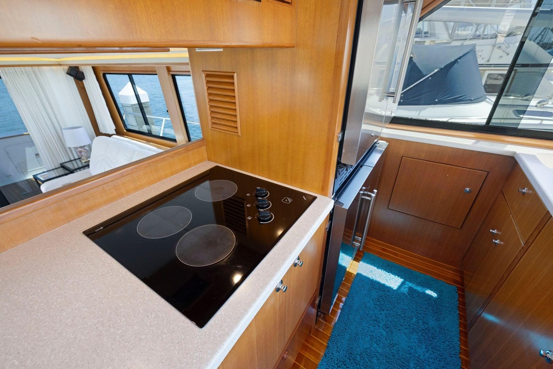 Luxurious yacht kitchen interior with modern stovetop, wood cabinetry, and ocean view. Symbol 55, 1999.