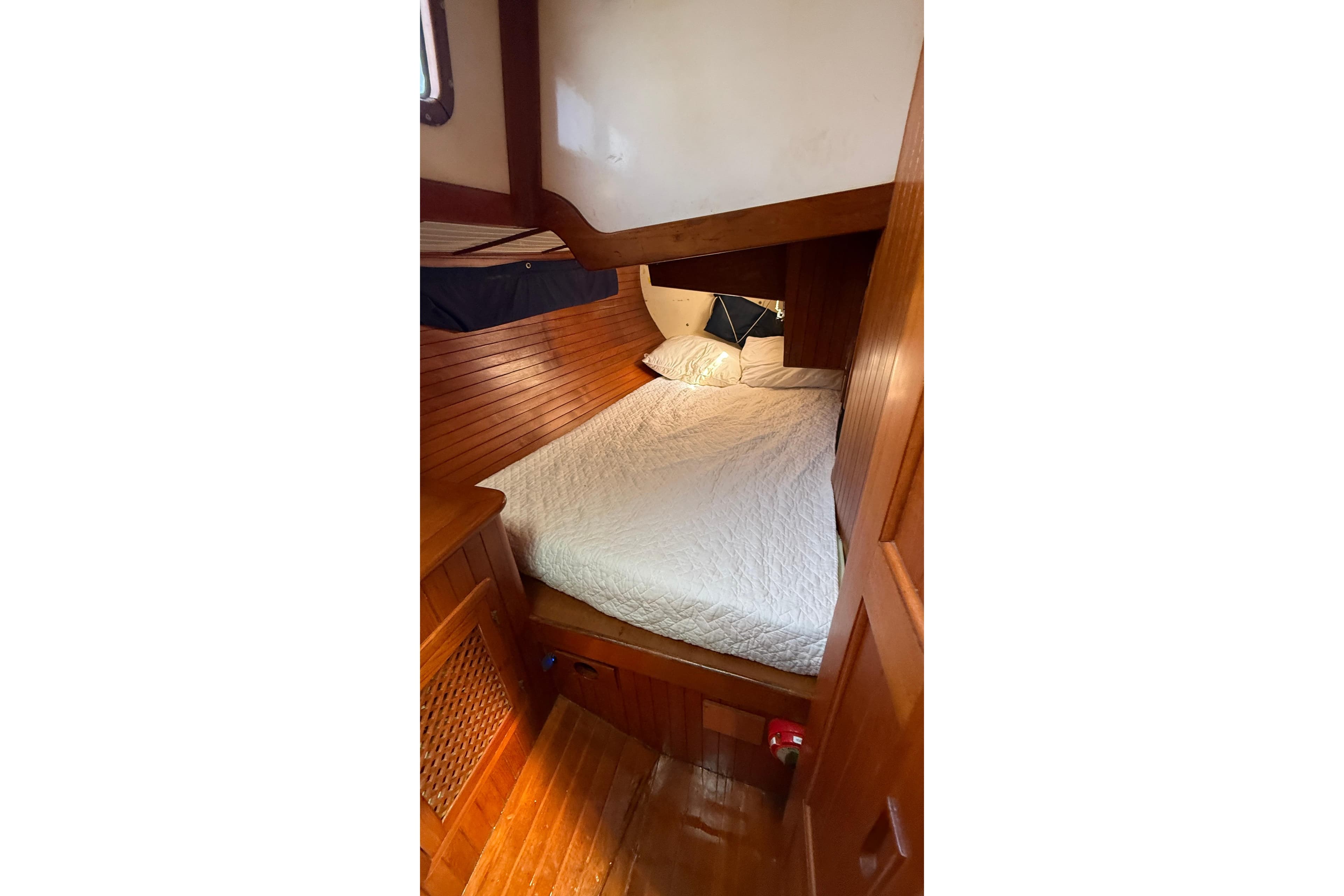 Cozy cabin interior of 1986 Westwind 38 sailboat with wooden paneling and comfortable bedding.