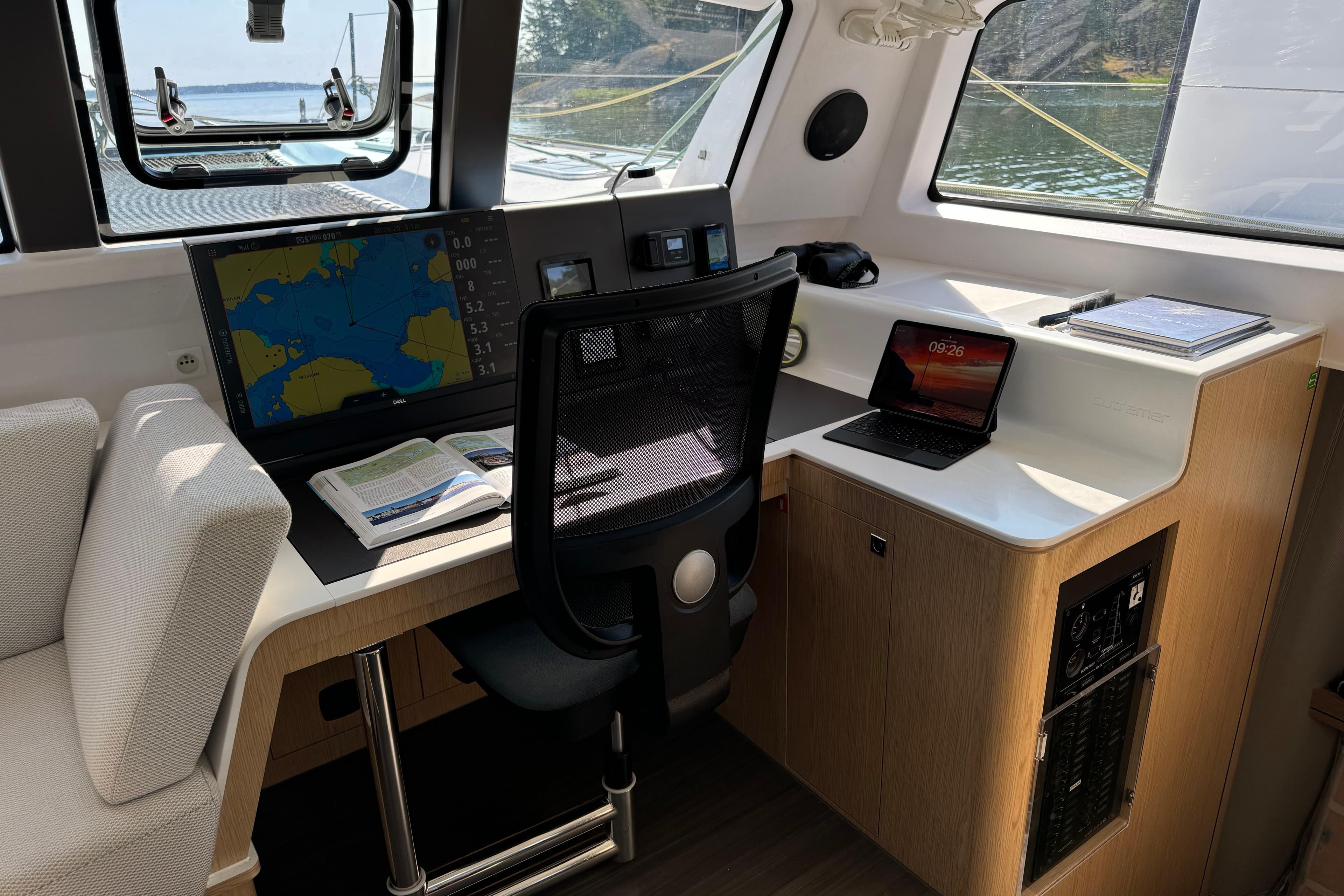 Modern navigation station inside 2022 Outremer 51 yacht with charts and laptop.