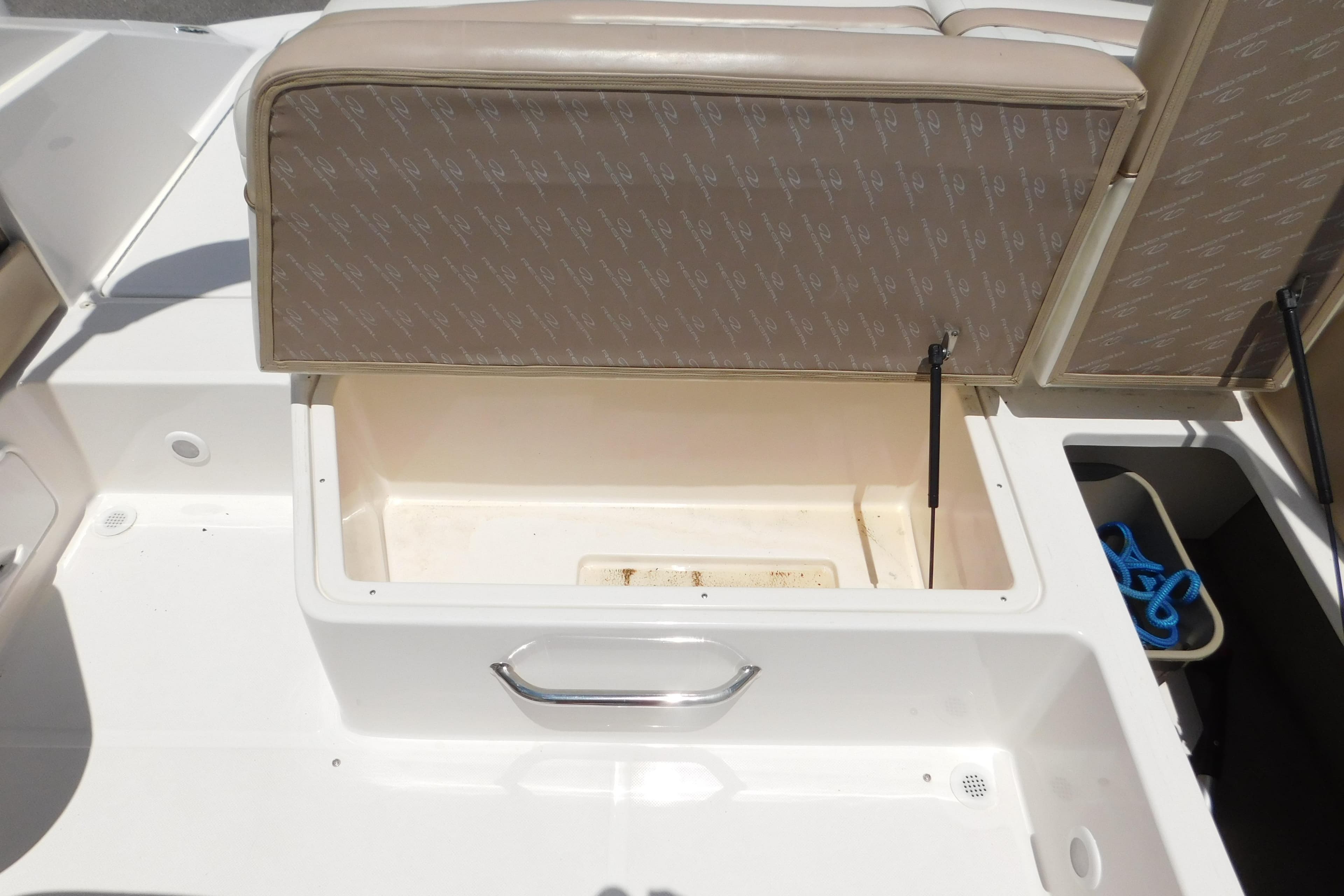 Open storage compartment on a 2004 Regal 2250 LSC boat, featuring beige upholstery.