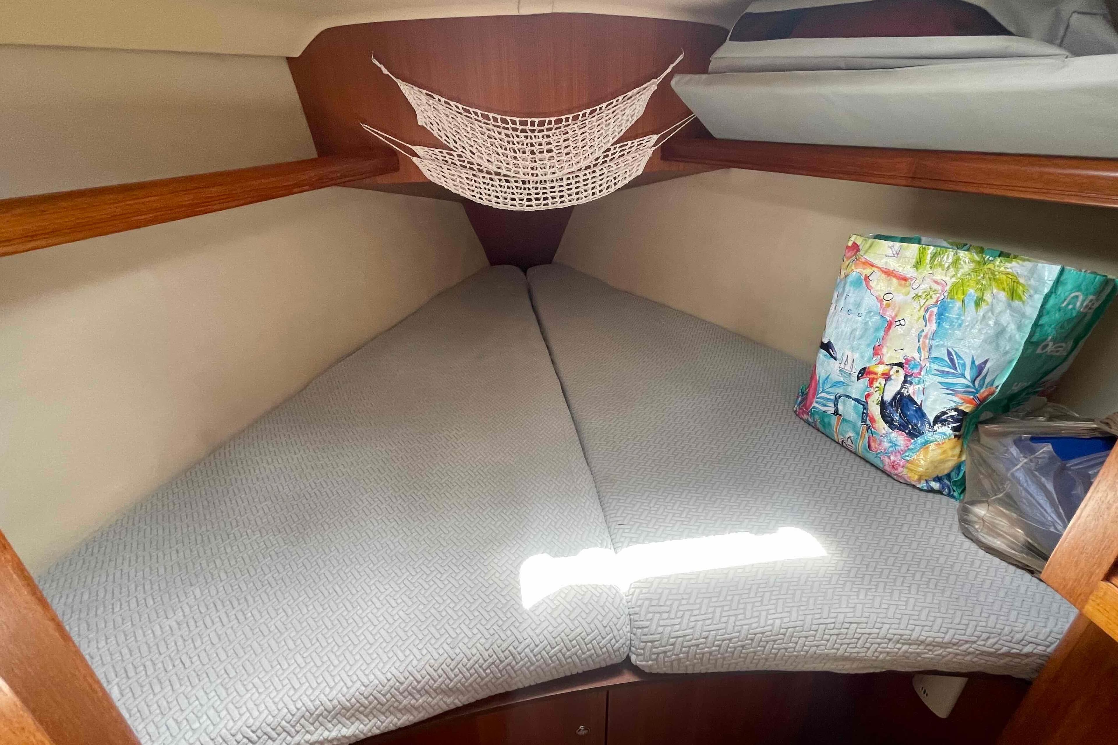 Cozy cabin interior of 2004 Hunter 36 sailboat with storage net and colorful bag.