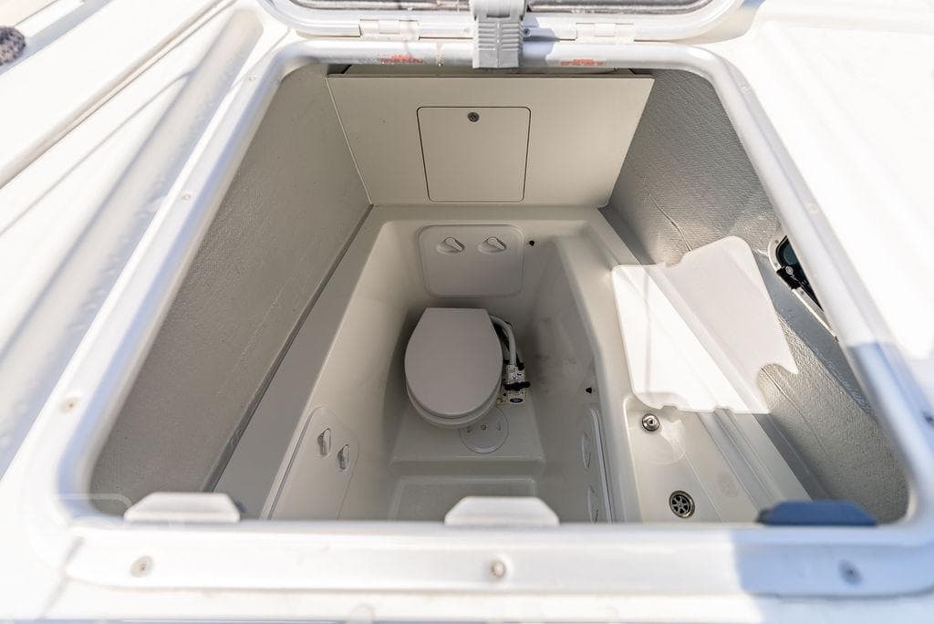 2021 Lagoon 46 yacht bathroom compartment with compact toilet and storage space.