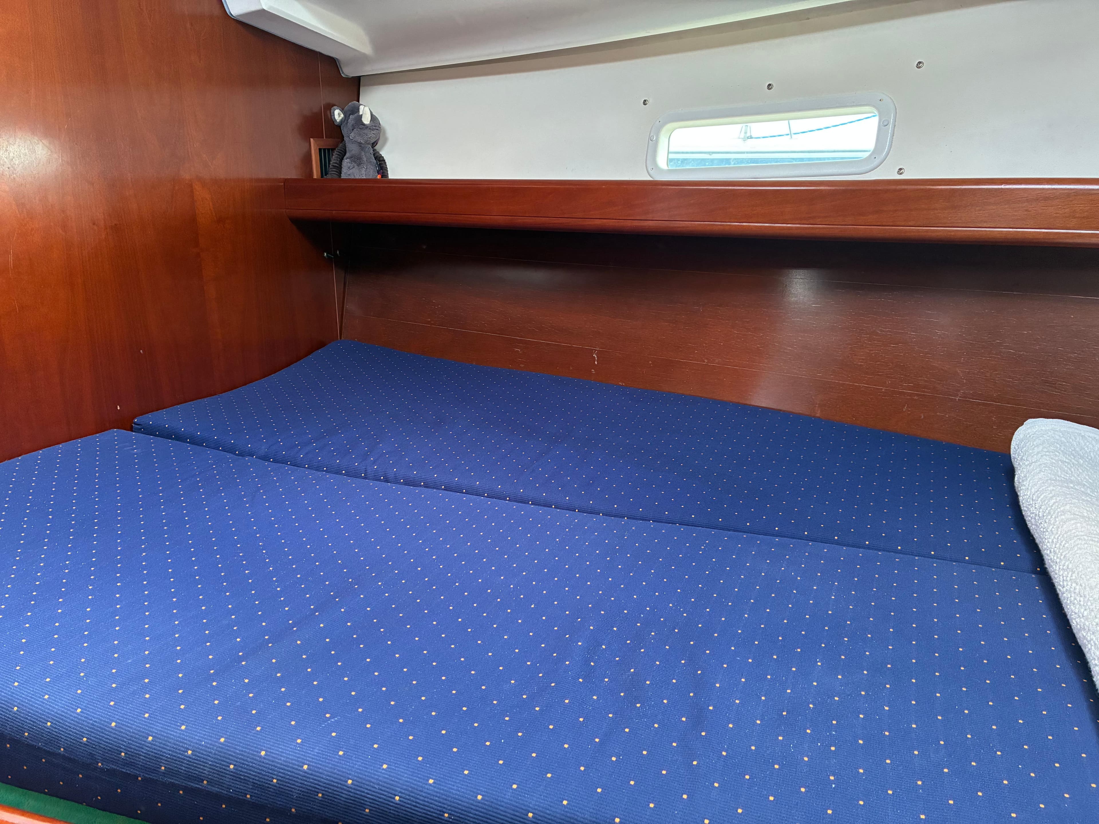 Cozy cabin interior of 2003 Beneteau Oceanis Clipper 393 with blue bedding and wooden finish.