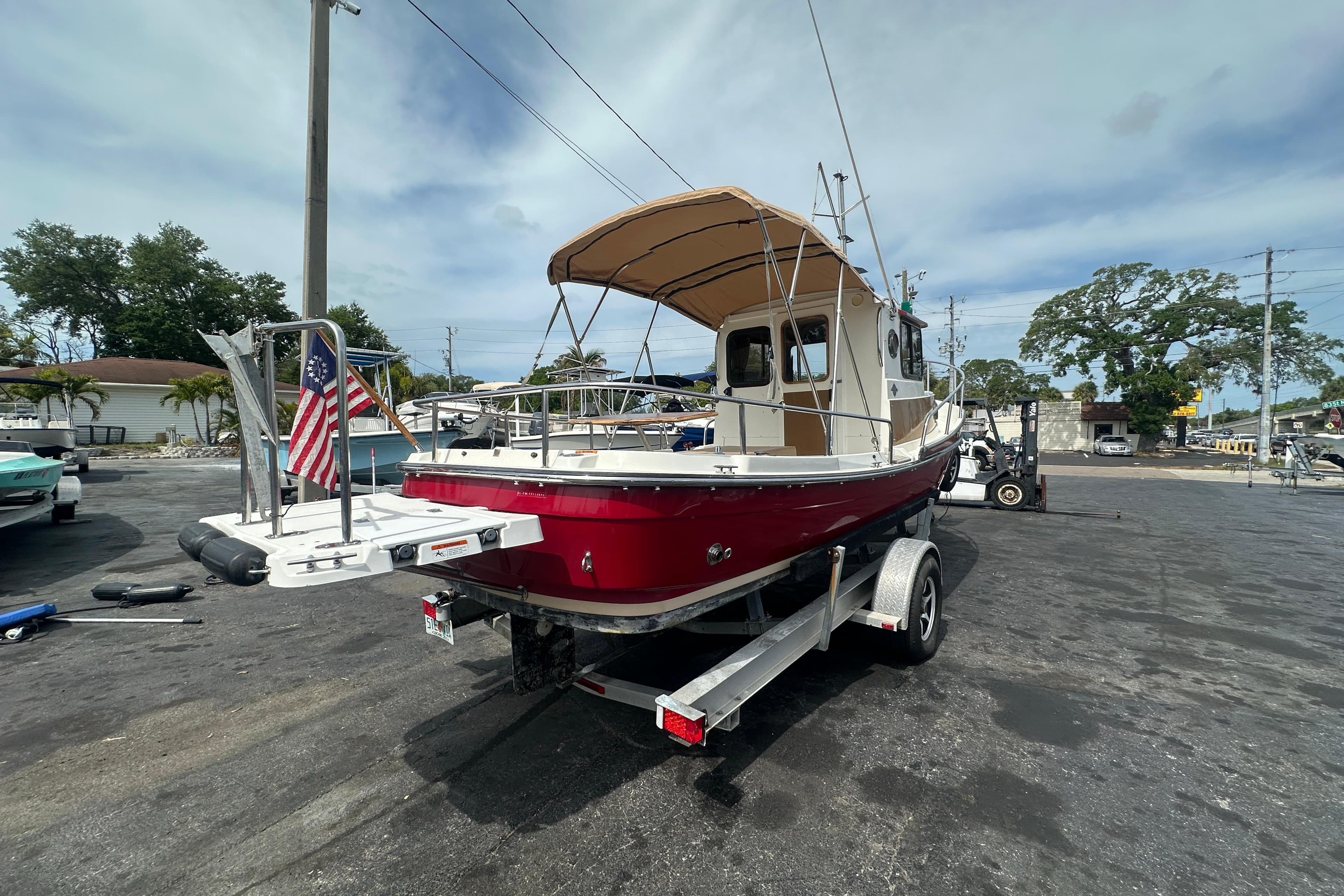 2015 Ranger Tugs R-21 EC boat on trailer, featuring red hull and American flag.