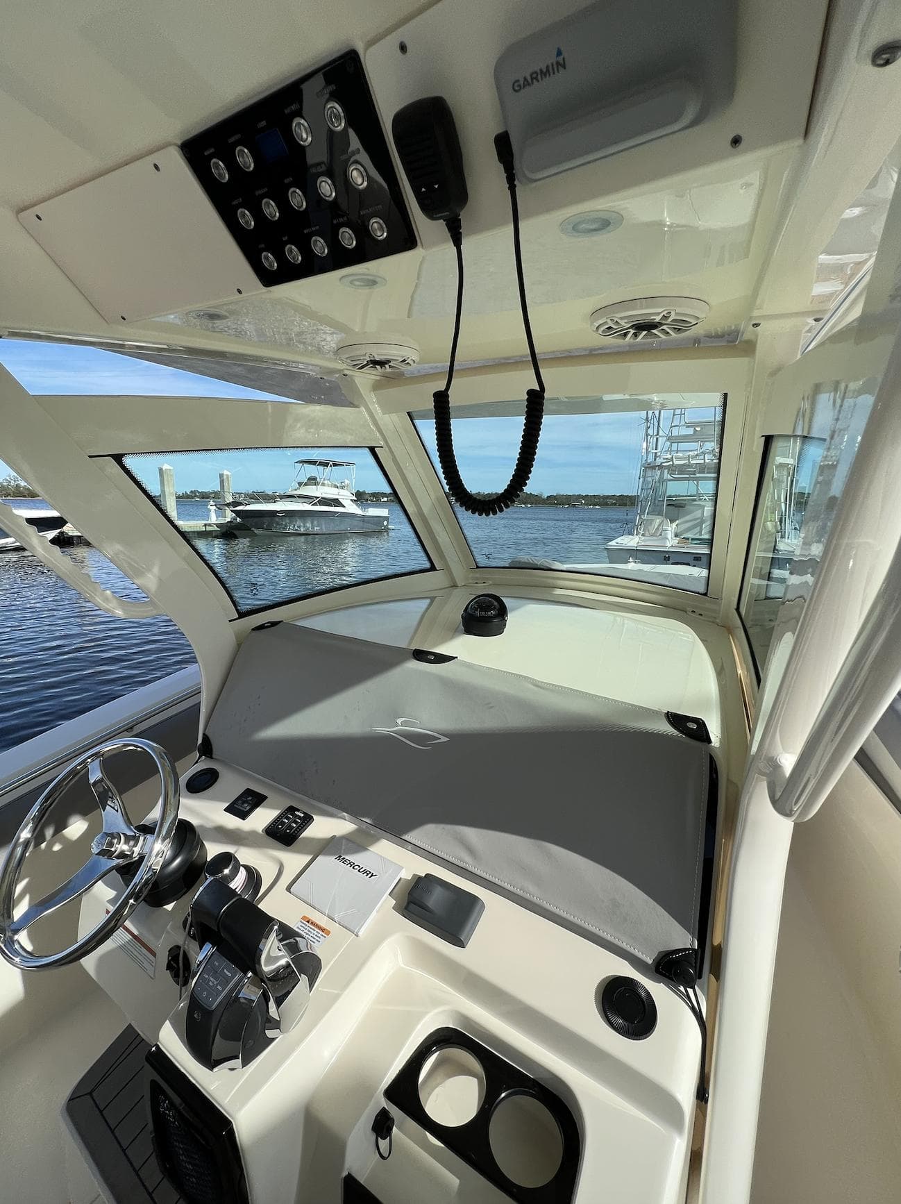 2021 Scout 305 LXF boat interior with steering wheel and control panel, docked by the water.