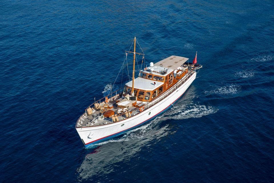 Vintage 1958 Feadship Custom 25m yacht cruising on open blue sea.