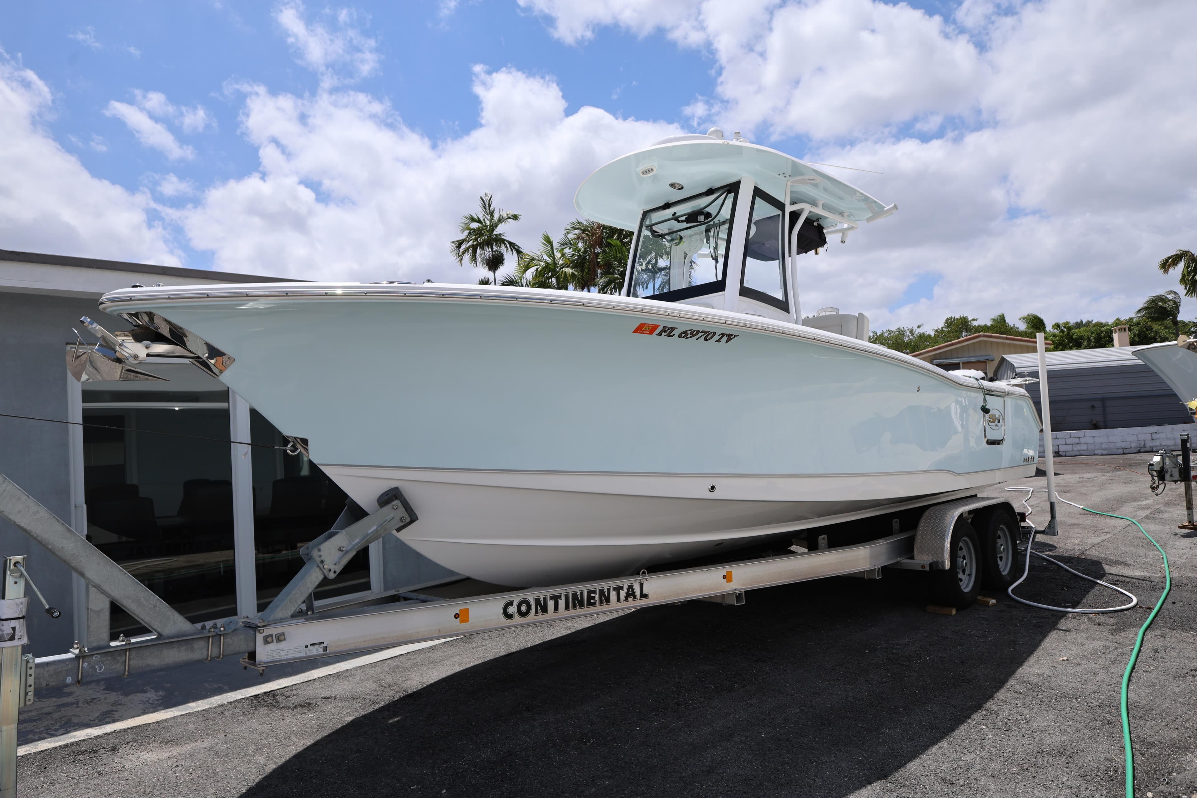 2024 Sea Hunt Gamefish 25 boat on trailer, parked outdoors under cloudy sky.
