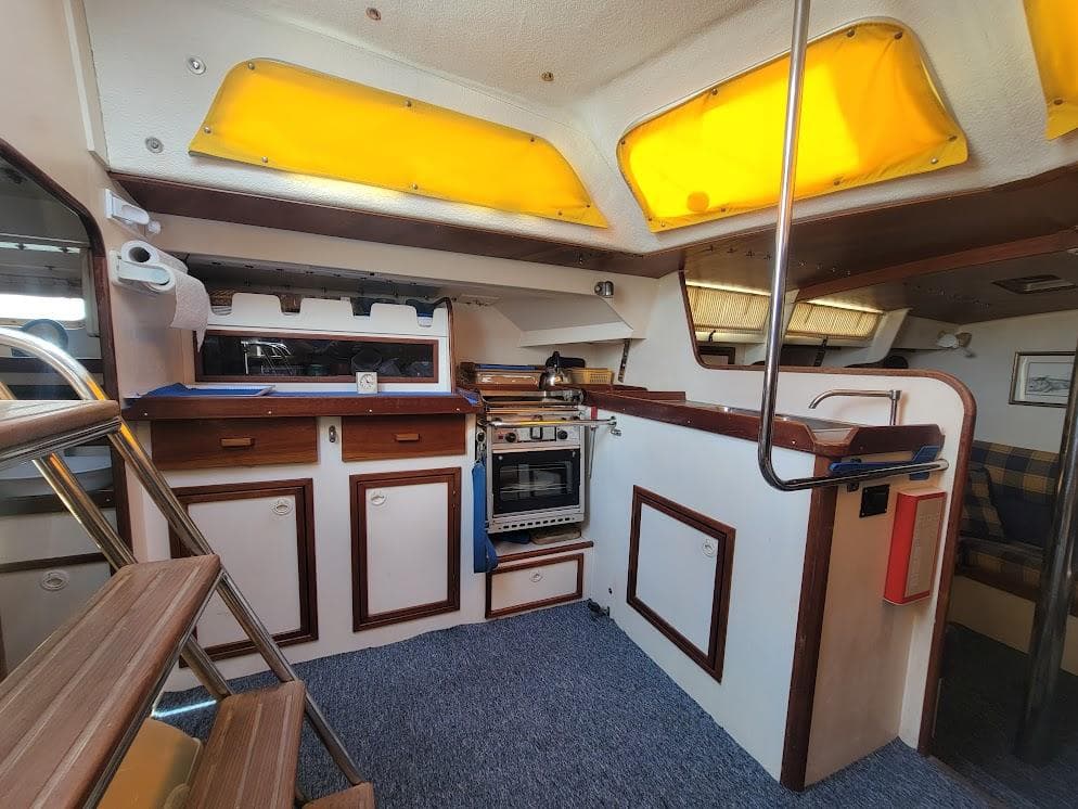 Cozy interior of 1999 Simpson Custom Andrew Simpson RQC 38 yacht with kitchen and seating area.