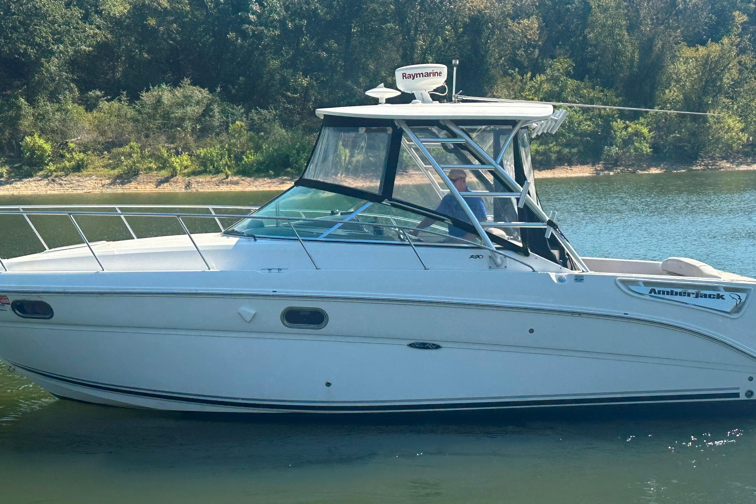 2008 Sea Ray 290 Amberjack boat on calm water, surrounded by lush greenery.