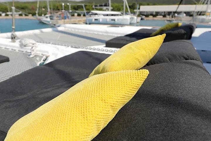 Luxurious Lagoon 620 Esense 2018 yacht deck with yellow cushions and scenic marina view.
