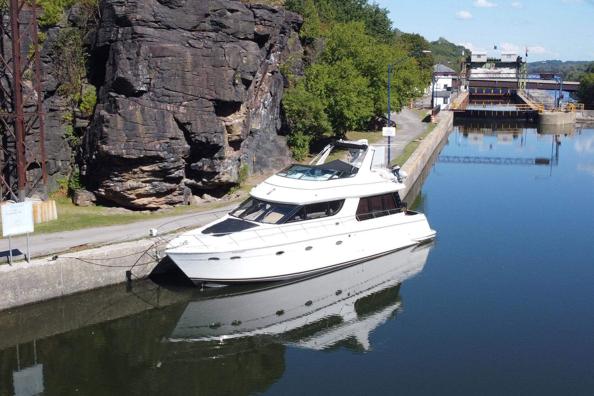 1999 Carver 530 Voyager Pilothouse yacht docked by rocky shoreline.