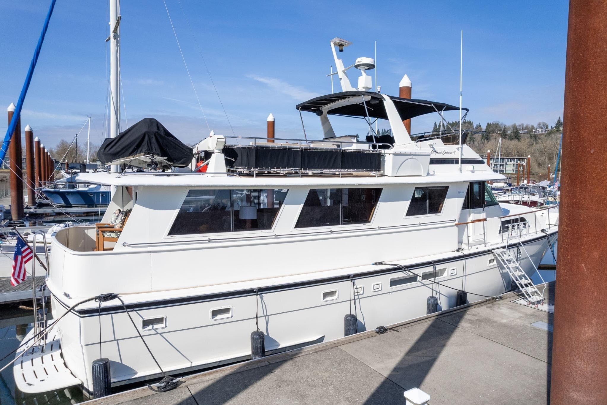 1986 Hatteras 63 Motor Yacht docked at marina under clear blue sky.