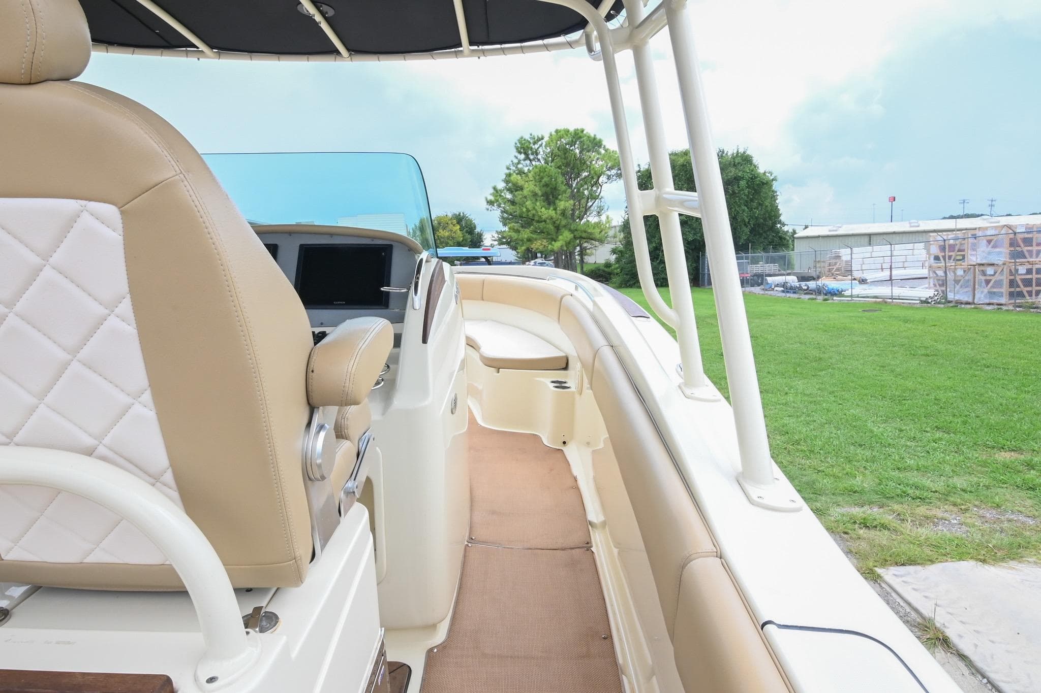 2016 Chris-Craft Catalina 29 boat interior with tan seating and helm, parked on grass.