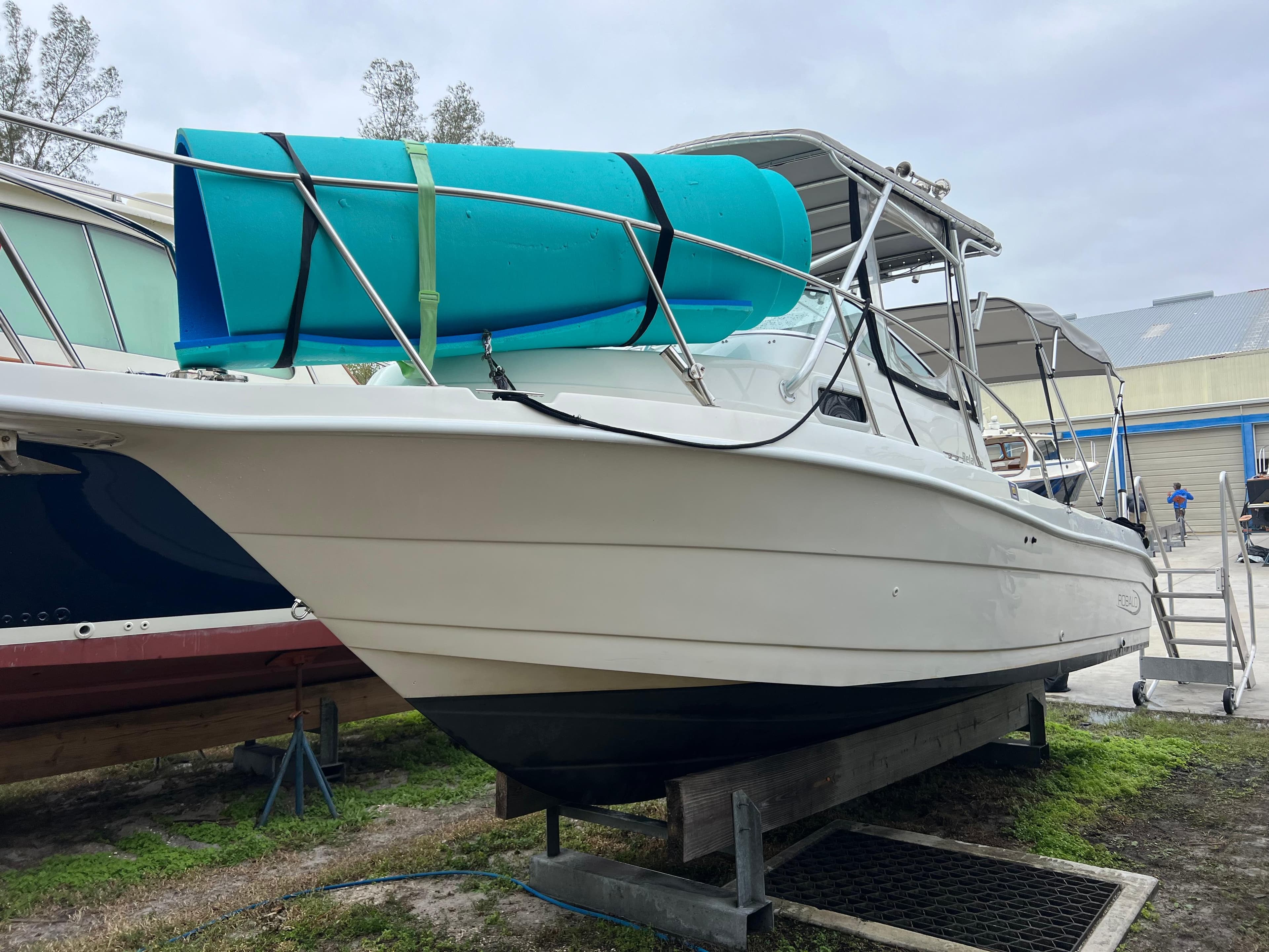 2000 Robalo 2440 Walkaround boat on trailer with blue tarp.
