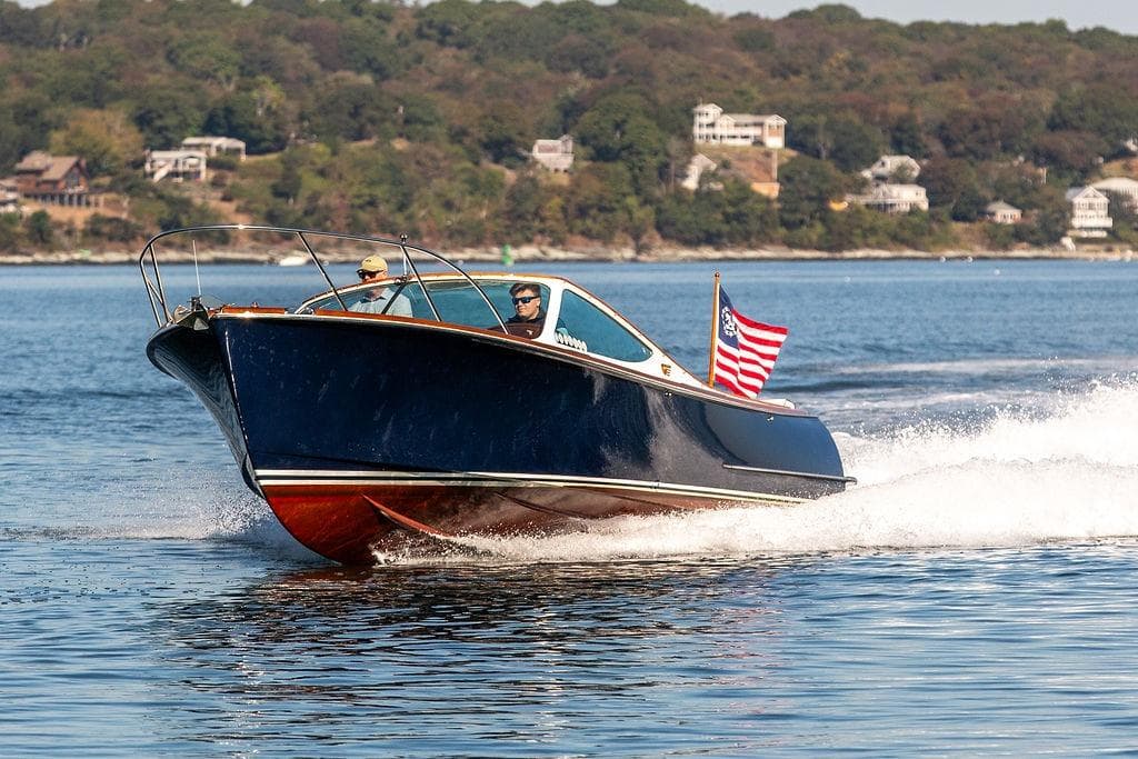 2003 Hinckley T29R boat cruising on a scenic lake with American flag.