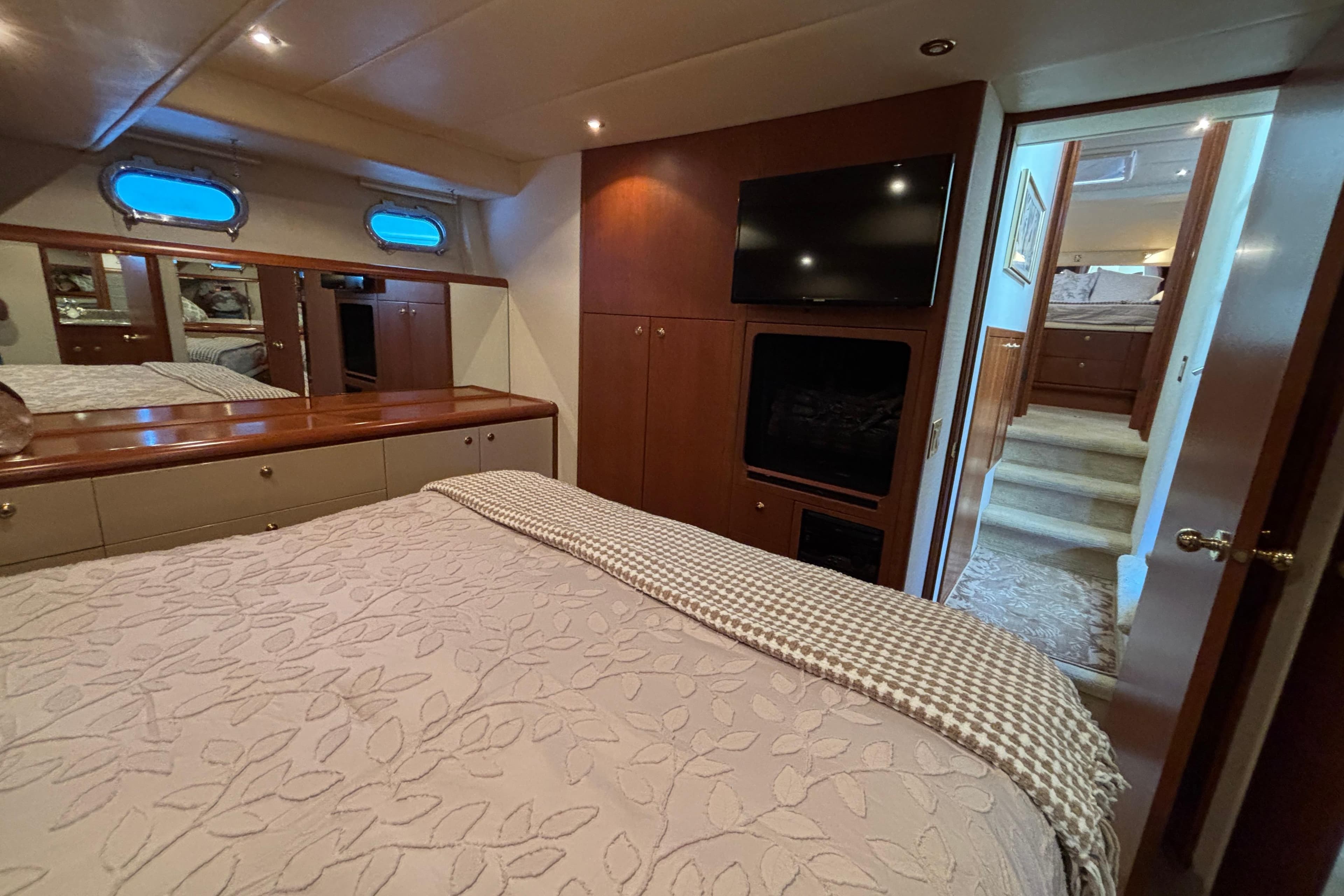 Luxurious 1996 Queenship yacht bedroom with TV, elegant decor, and cozy bedding.