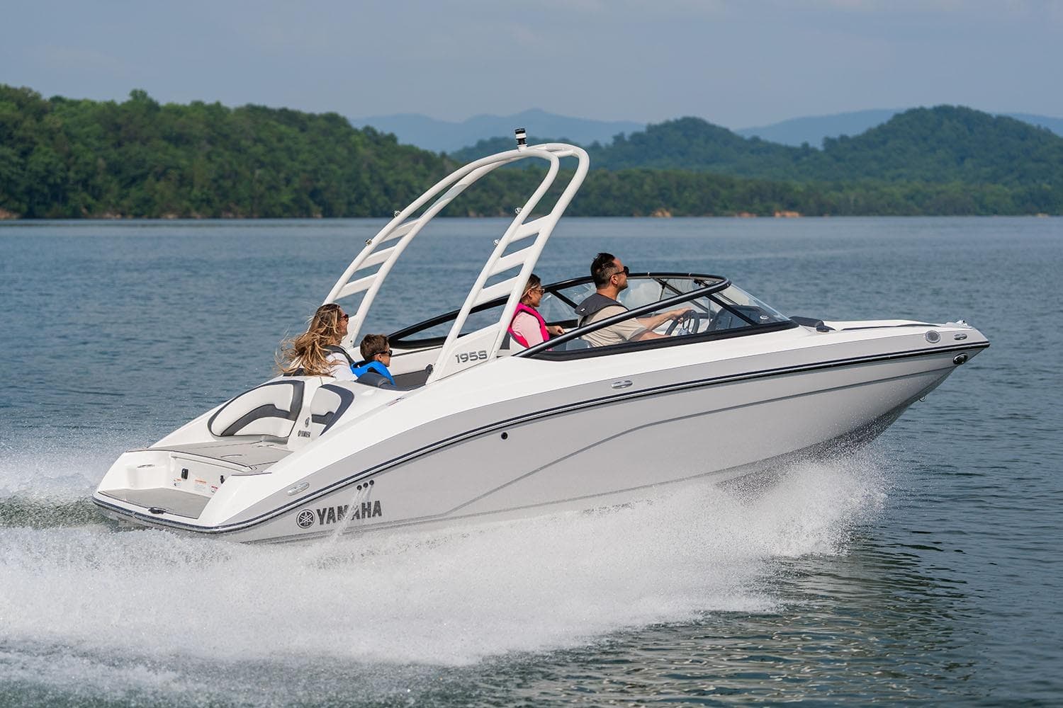 Manufacturer Provided Image: 2026 Yamaha Boats 195S cruising on a lake with passengers, surrounded by scenic hills.