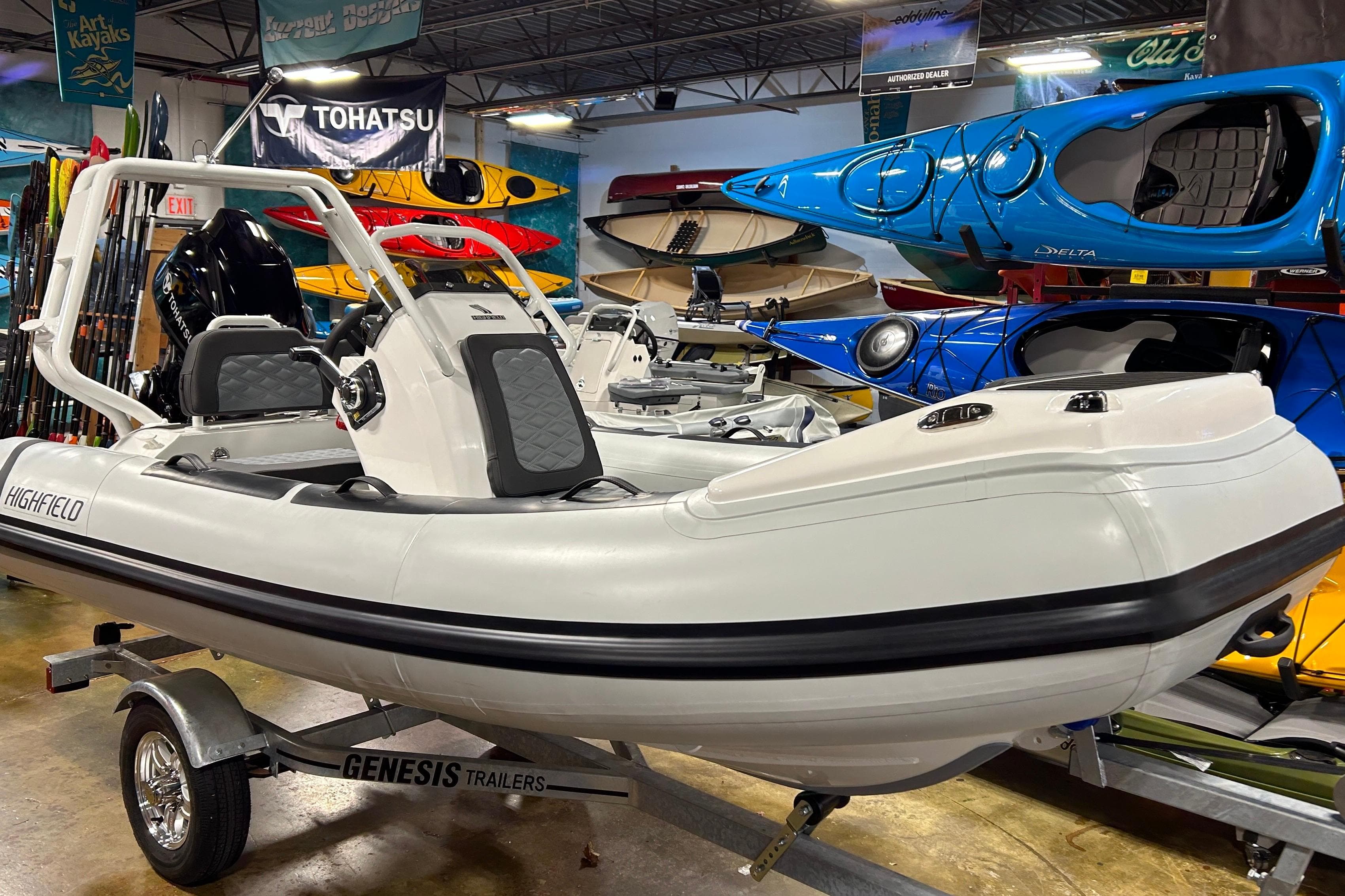 2026 Highfield Sport 390 boat on Genesis trailer in showroom with kayaks.